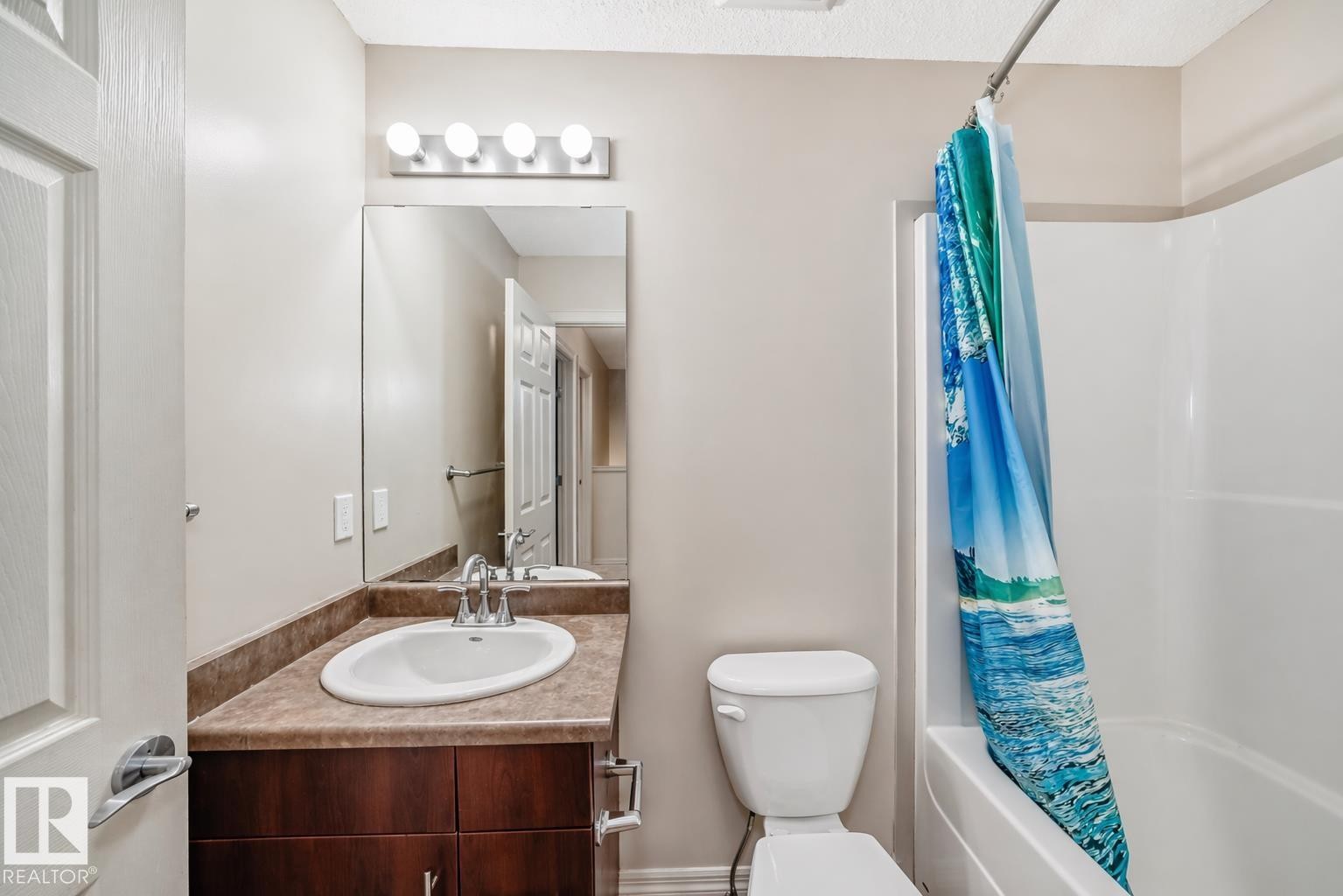 Full bathroom featuring a dark wood-finish vanity with an integrated sink, a large mirror, and a full bathtub with shower - 1285 Cunningham Drive, Edmonton, AB - Indoor Photo Showing Bathroom