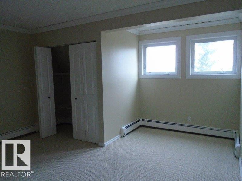 Unfurnished bedroom featuring crown molding, a baseboard heating unit, carpet, and a closet - 3041 Tudor Glen, St. Albert, AB