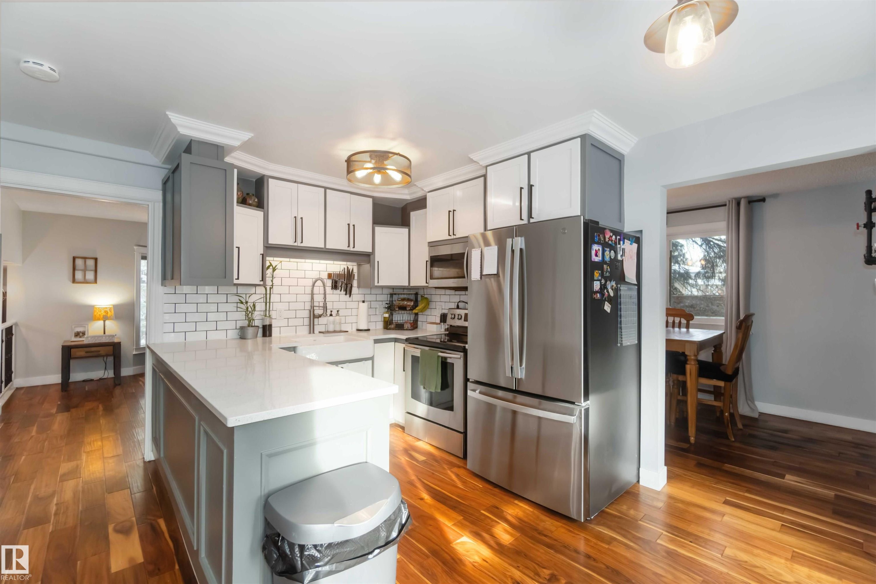 Kitchen featuring stainless steel appliances, dark wood-type flooring, a peninsula, and tasteful backsplash - 6 Garraway Pl, St. Albert, AB - Indoor Photo Showing Kitchen With Upgraded Kitchen
