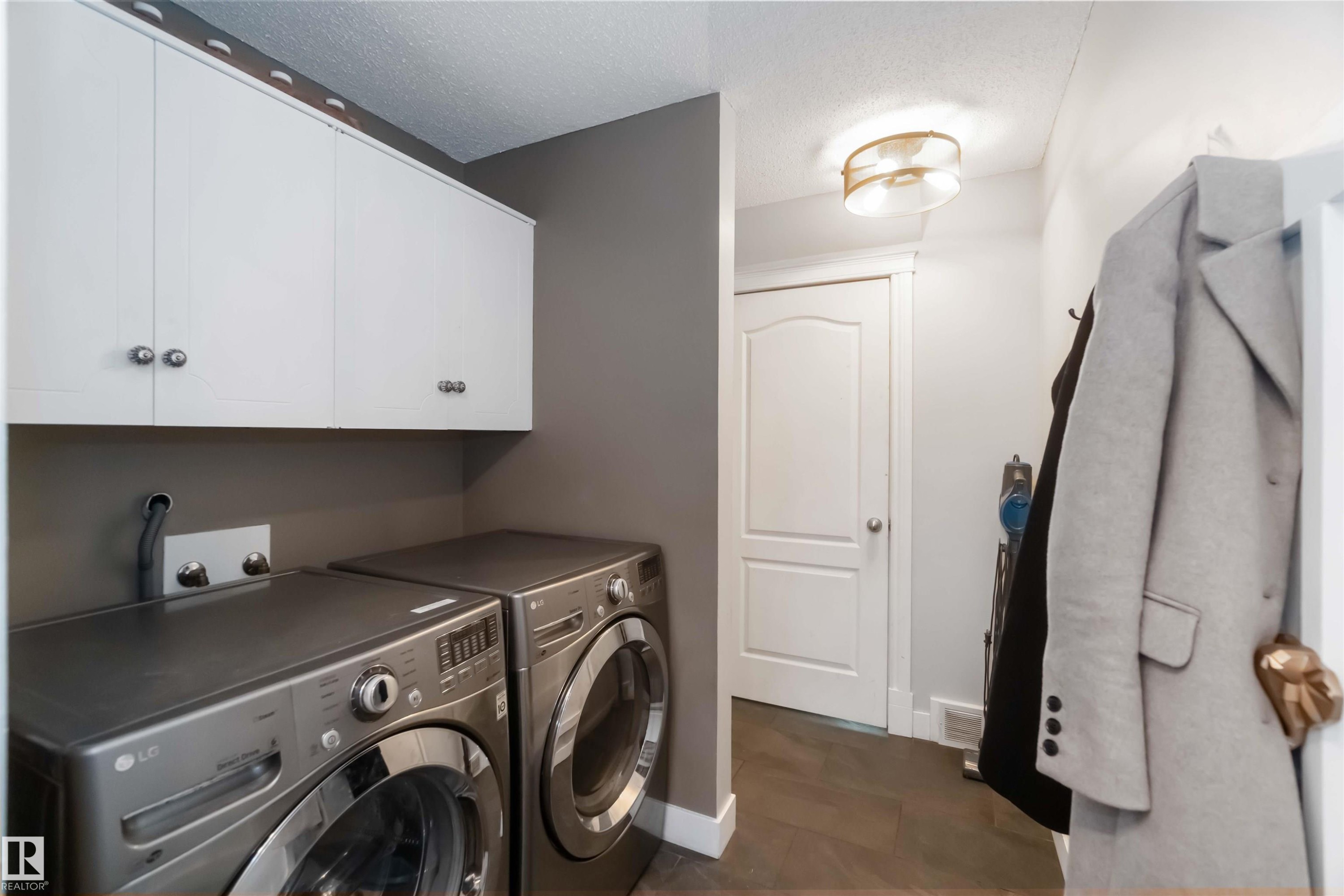 Laundry room featuring washer and clothes dryer, a textured ceiling, and cabinet space - 6 Garraway Pl, St. Albert, AB - Indoor Photo Showing Laundry Room