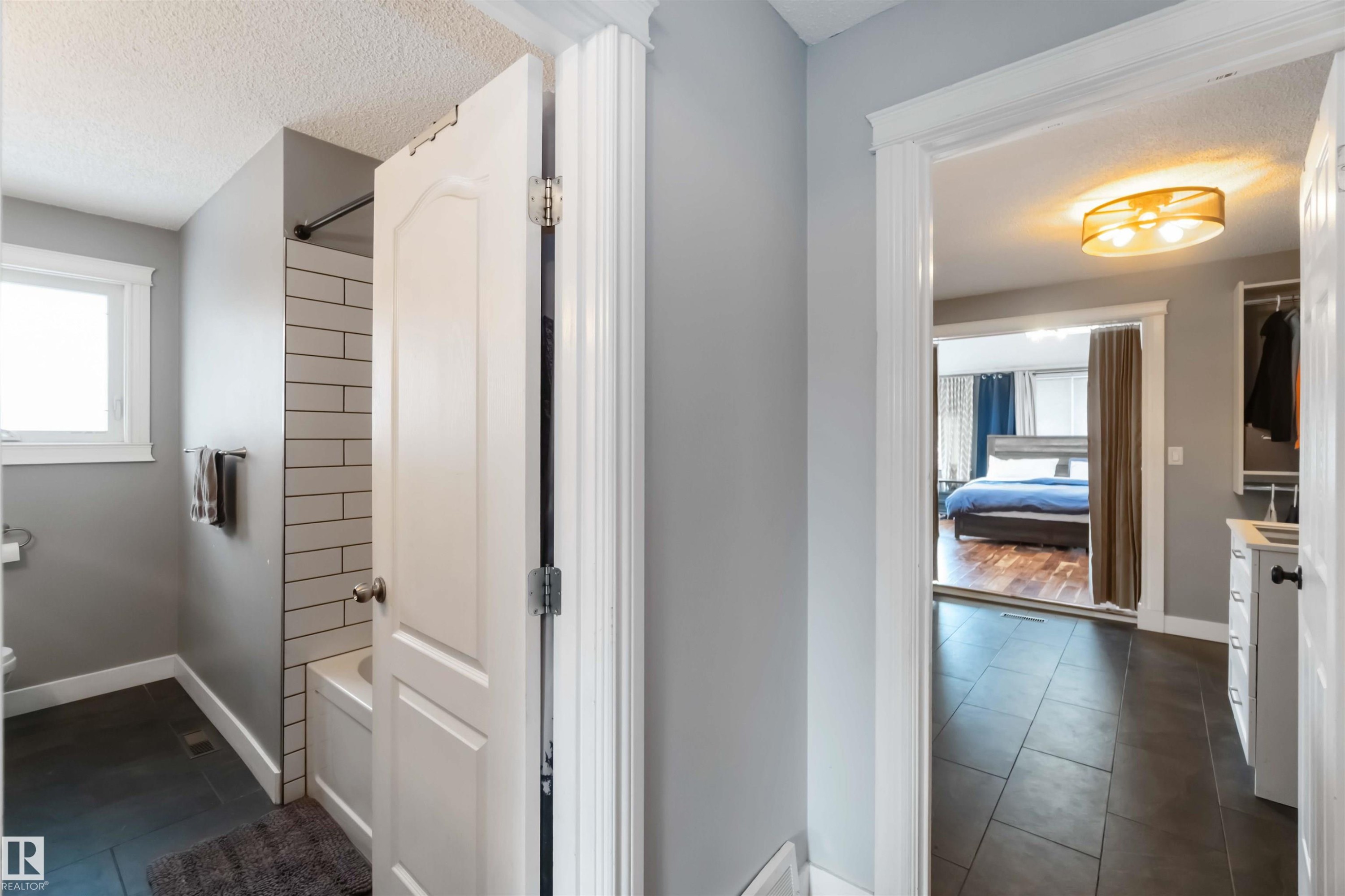 Bathroom with shower combination, a textured ceiling, dark tile patterned flooring, vanity, and ensuite bathroom - 6 Garraway Pl, St. Albert, AB - Indoor Photo Showing Other Room