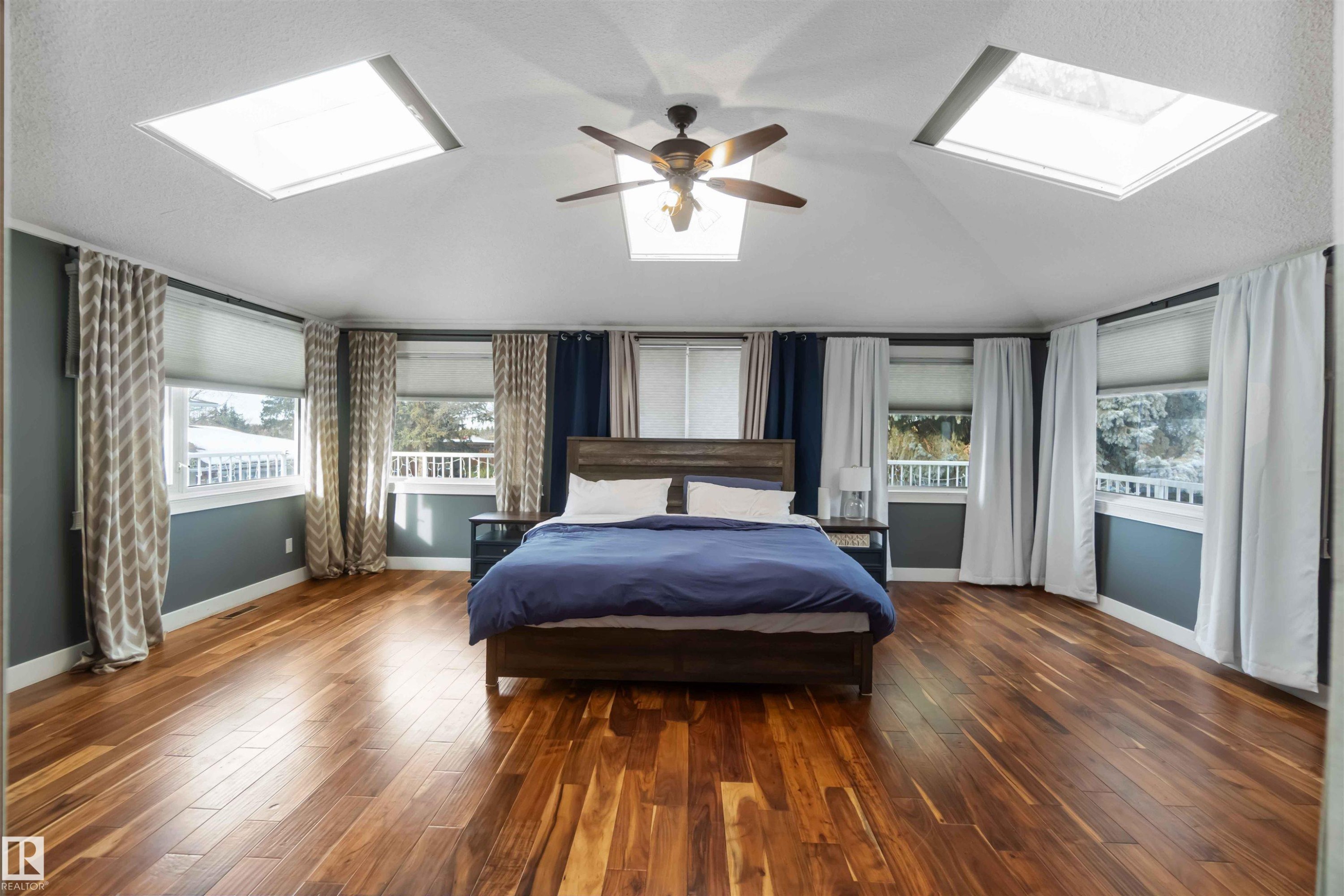 Bedroom featuring a skylight, hardwood / wood-style floors, a ceiling fan, multiple windows, and vaulted ceiling - 6 Garraway Pl, St. Albert, AB - Indoor Photo Showing Bedroom