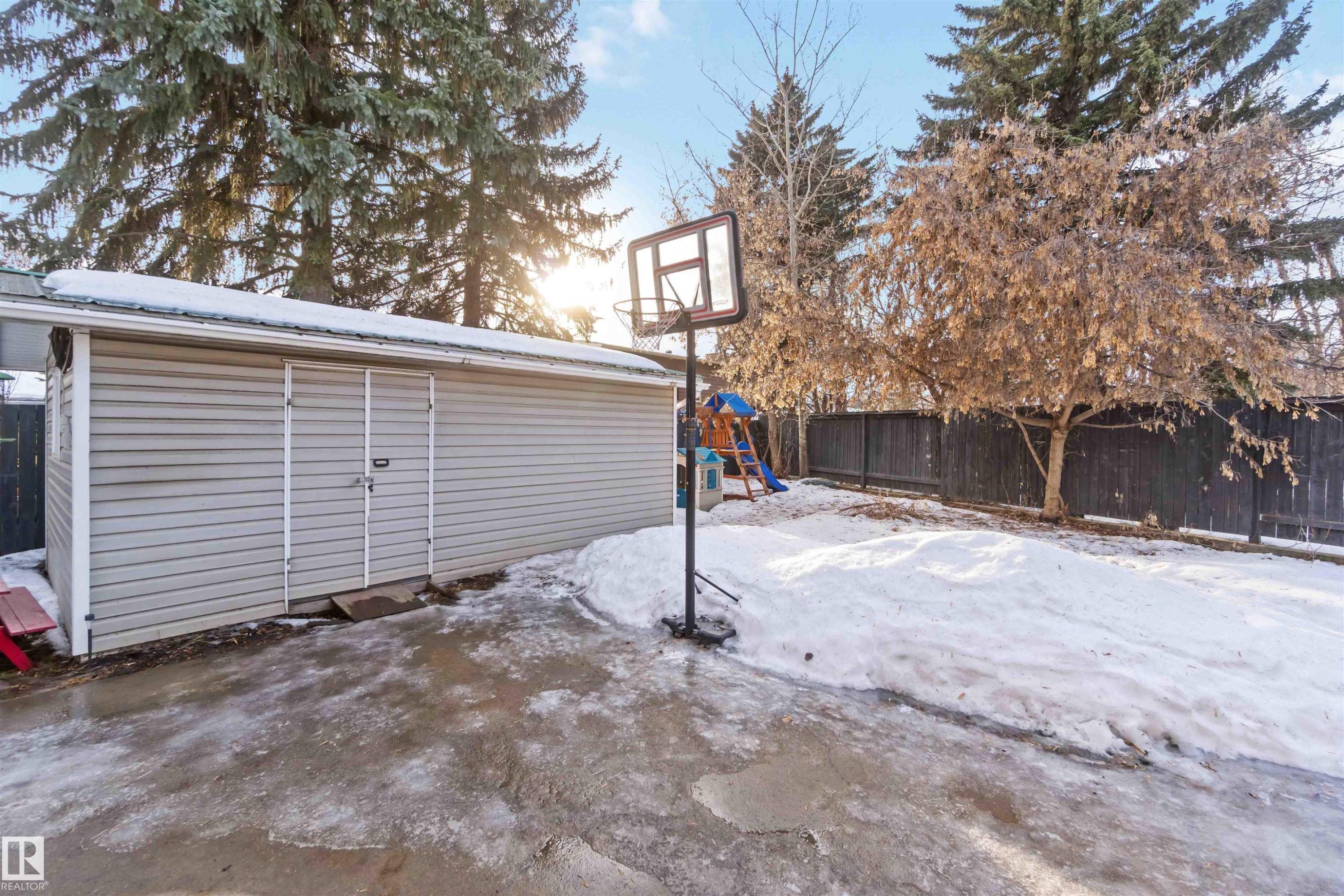 Snow covered patio with a playground, an outdoor structure, and a fenced backyard - 6 Garraway Pl, St. Albert, AB - Outdoor
