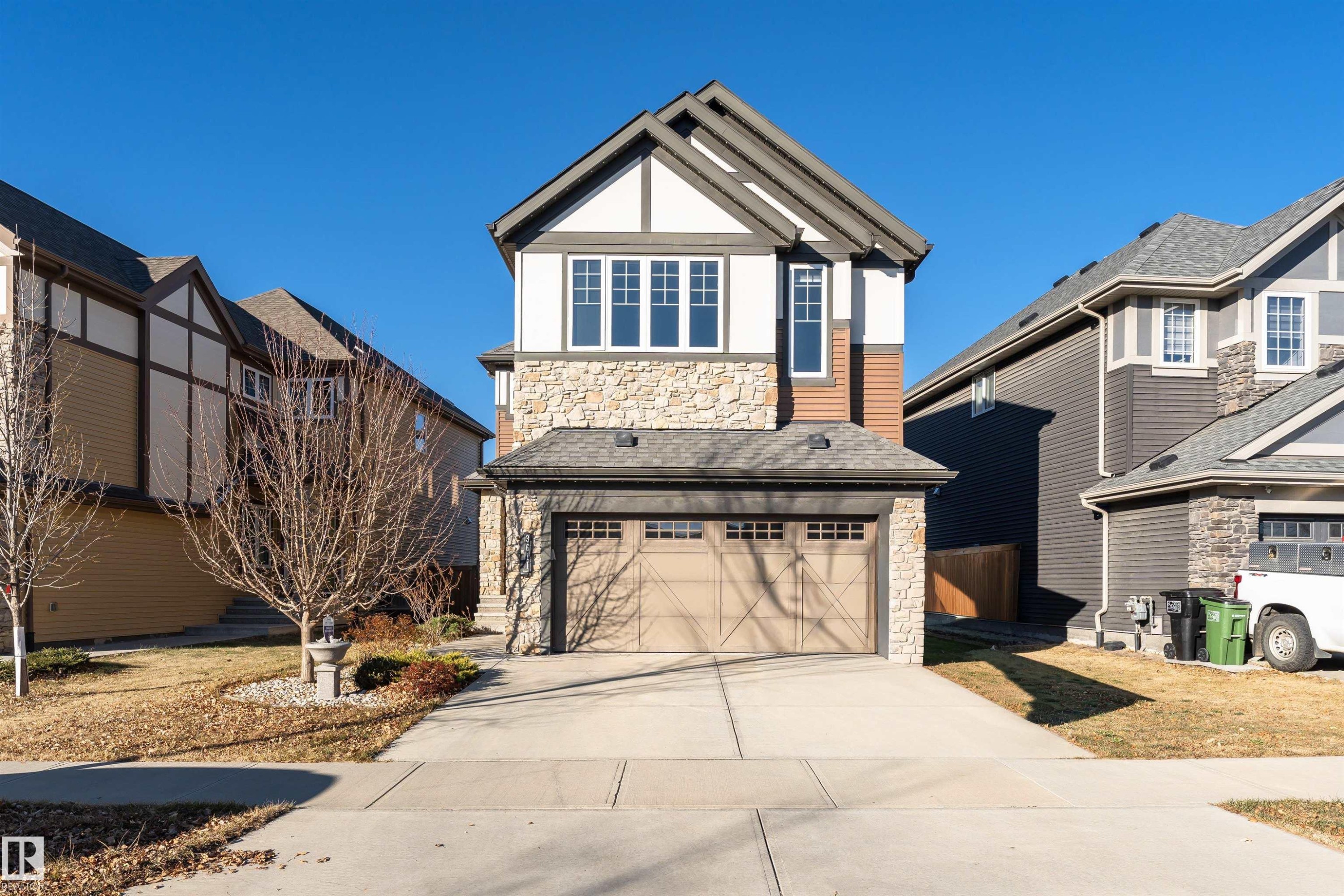 View of front facade featuring stone siding, an attached garage, and concrete driveway - 3611 Keswick Boulevard, Edmonton, AB - Outdoor