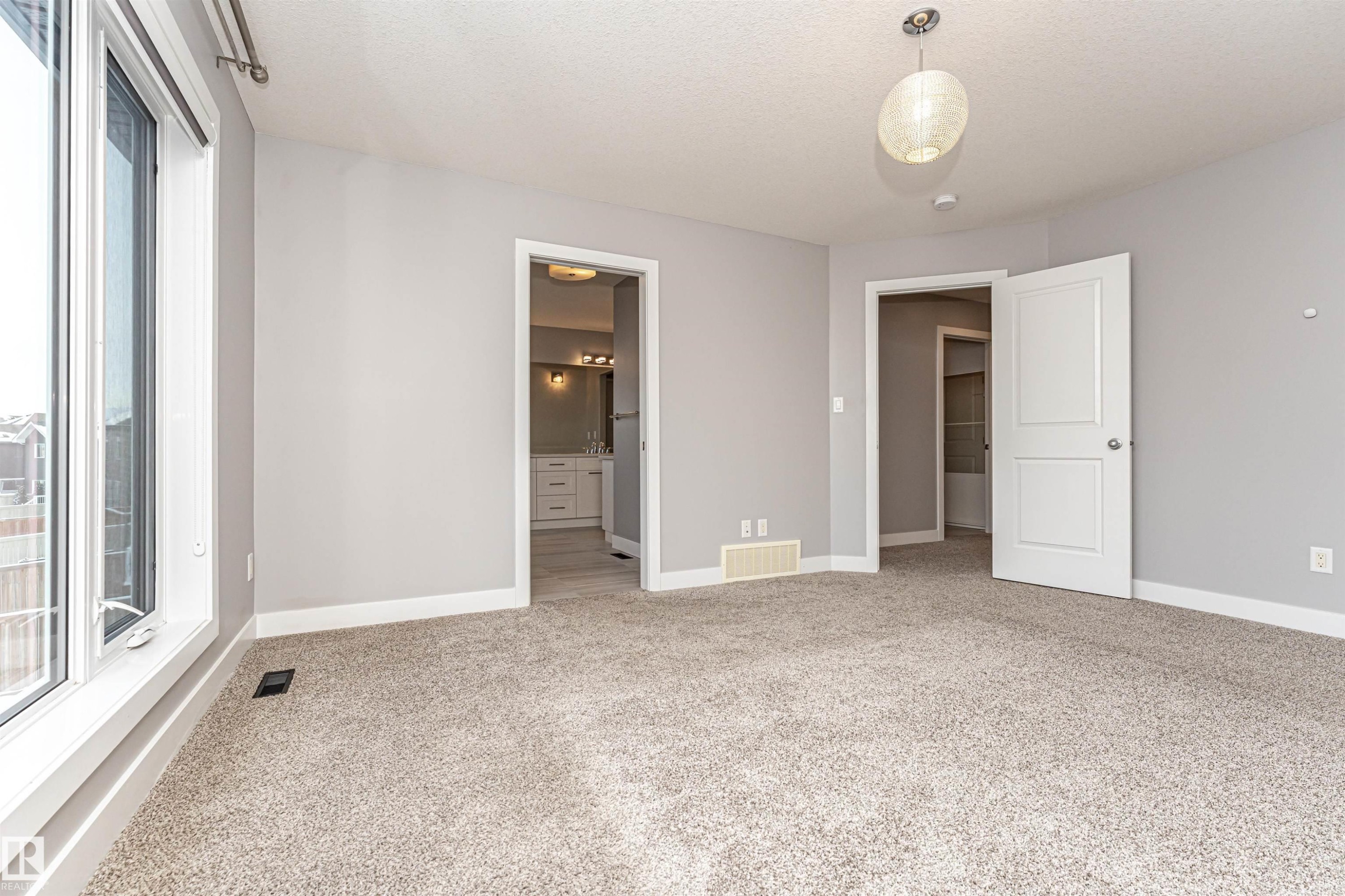 Unfurnished bedroom with light colored carpet, ensuite bath, and a textured ceiling - 3611 Keswick Boulevard, Edmonton, AB - Indoor Photo Showing Other Room