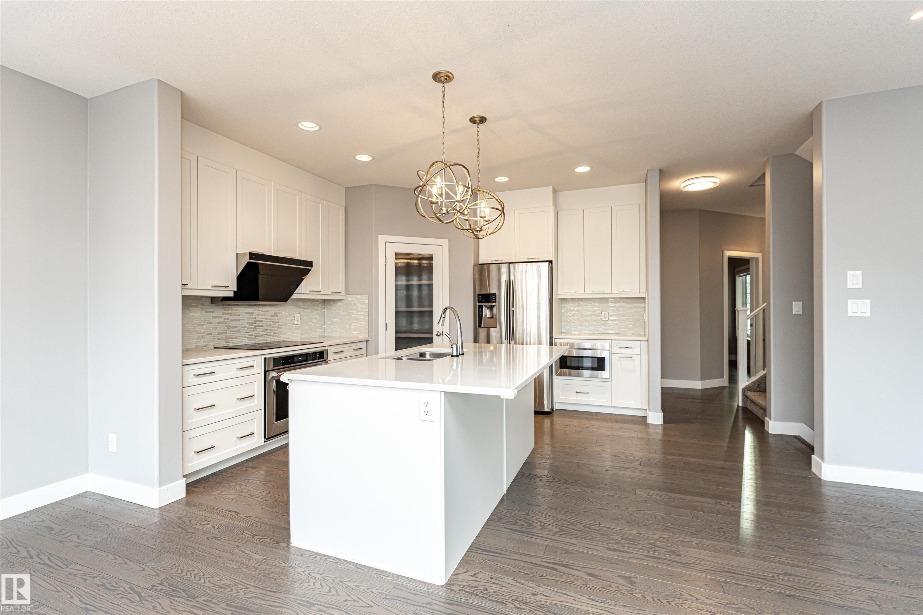 Kitchen with white cabinetry, a kitchen island with sink, suspended lighting, and stainless steel appliances - 3611 Keswick Boulevard, Edmonton, AB - Indoor Photo Showing Kitchen With Upgraded Kitchen