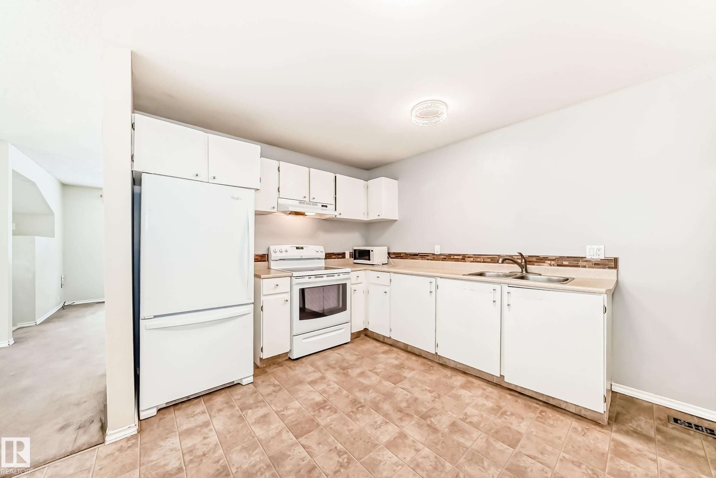 Kitchen with white appliances, white cabinetry, and light countertops - 5308 20 Avenue, Edmonton, AB - Indoor Photo Showing Kitchen With Double Sink