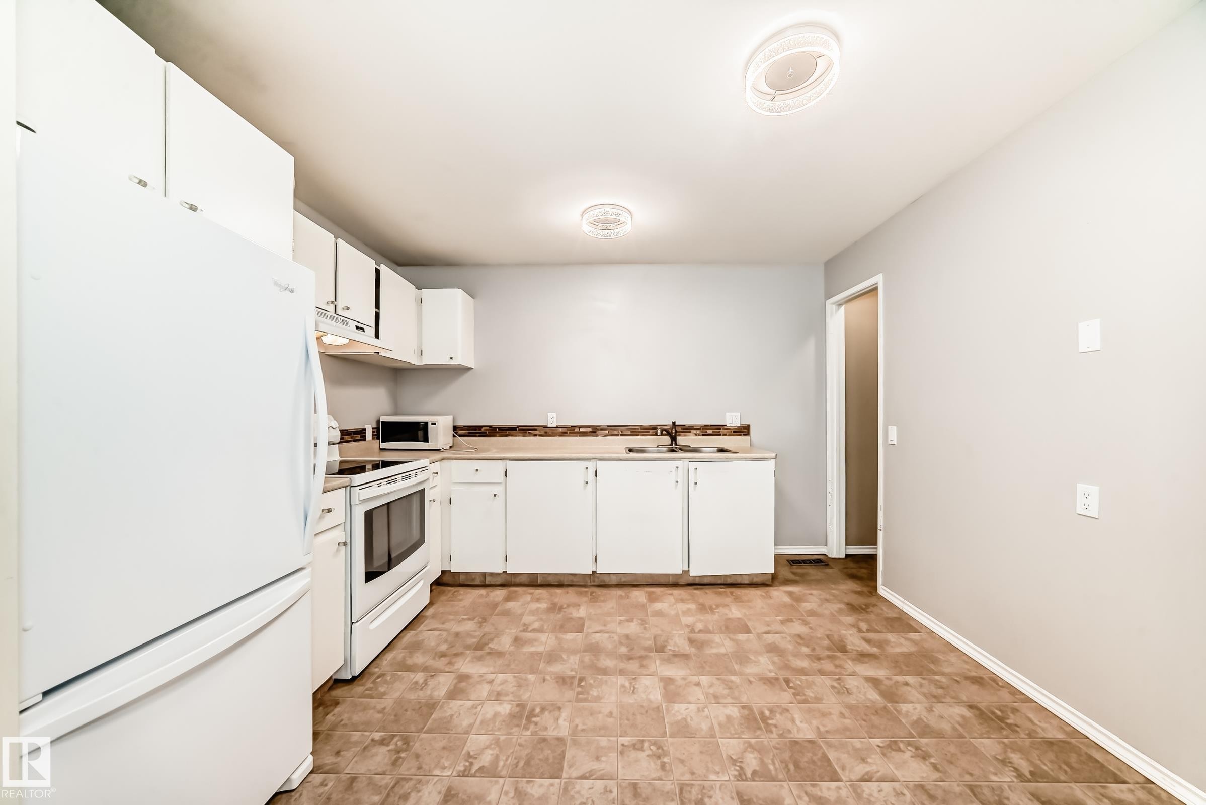 Kitchen featuring white appliances, white cabinets, and light countertops - 5308 20 Avenue, Edmonton, AB - Indoor Photo Showing Kitchen With Double Sink