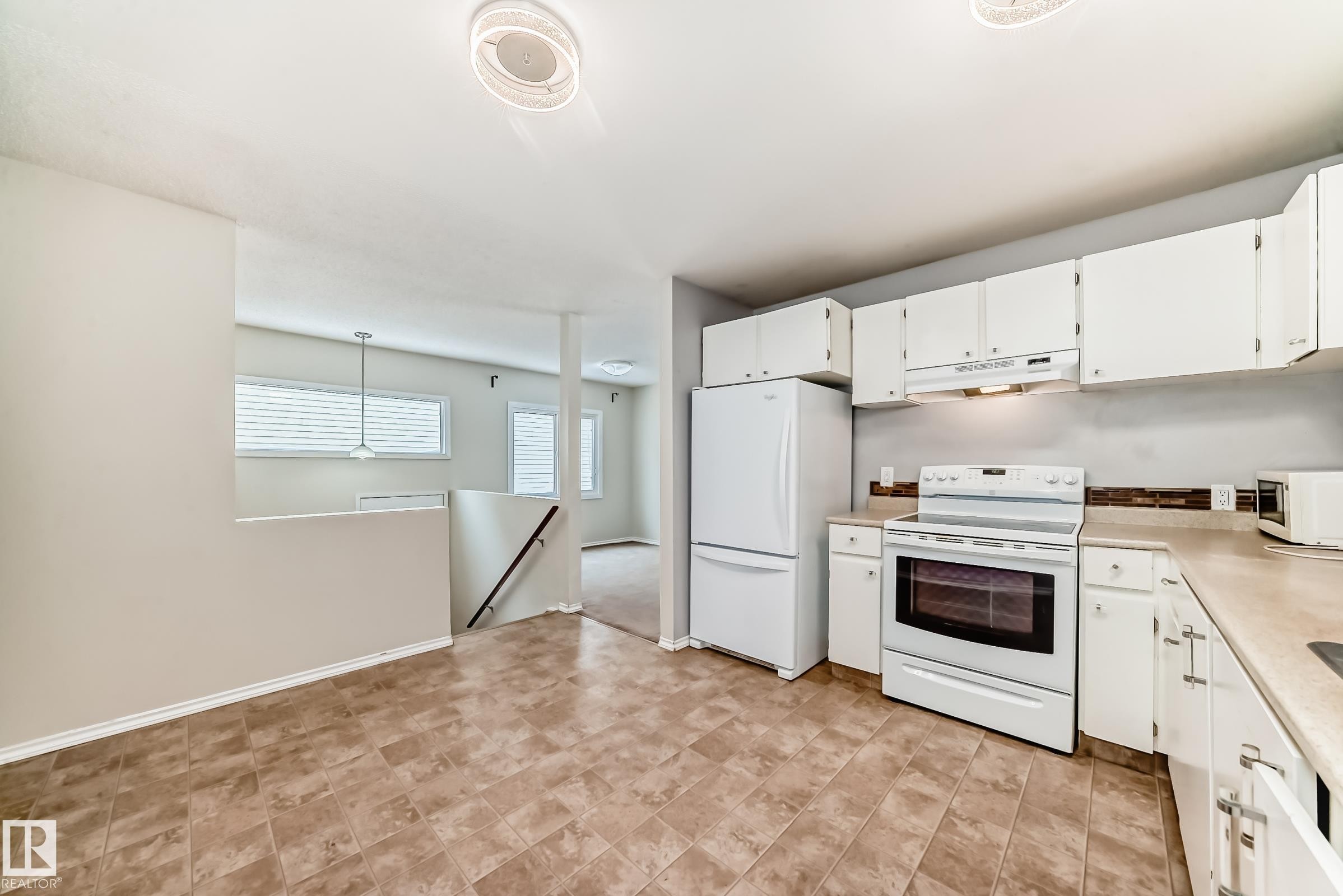 Kitchen featuring white appliances, white cabinets, light countertops, and decorative light fixtures - 5308 20 Avenue, Edmonton, AB - Indoor Photo Showing Kitchen