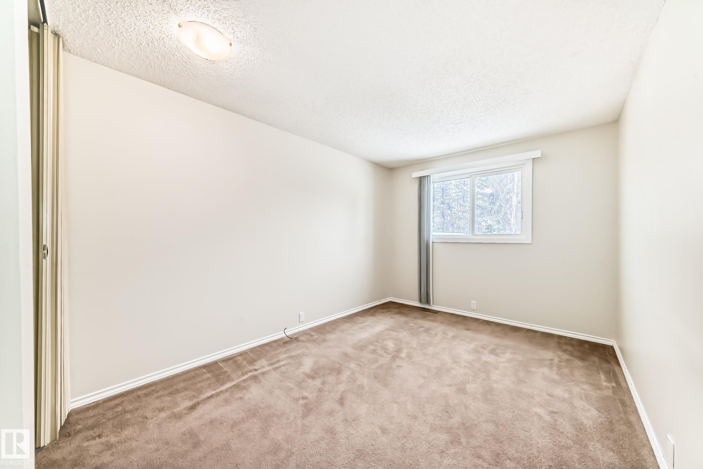 Empty room with light colored carpet and a textured ceiling - 5308 20 Avenue, Edmonton, AB - Indoor Photo Showing Other Room