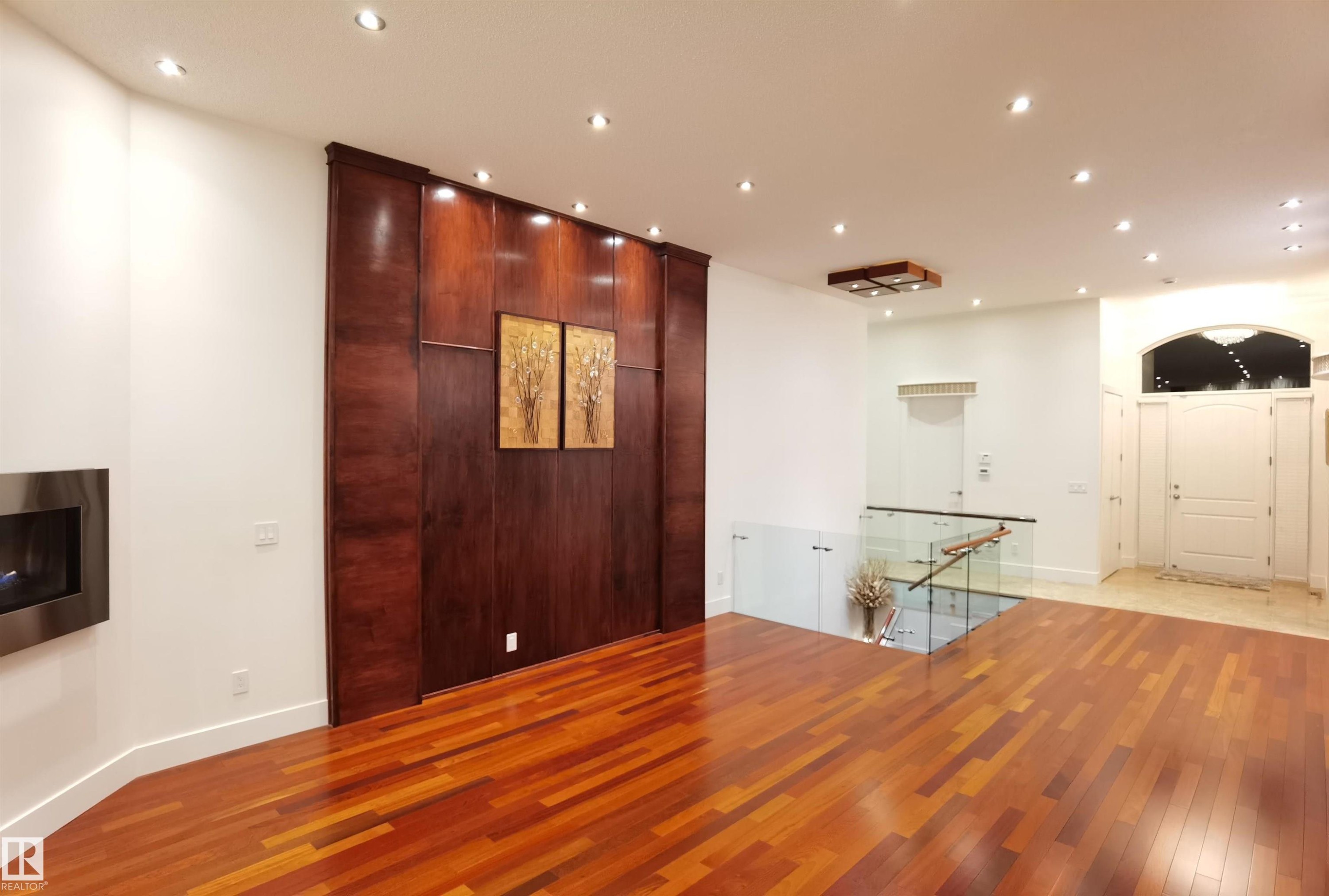 Unfurnished room with wood-type flooring, recessed lighting, and a glass covered fireplace - 169 Callaghan Drive, Edmonton, AB - Indoor Photo Showing Other Room