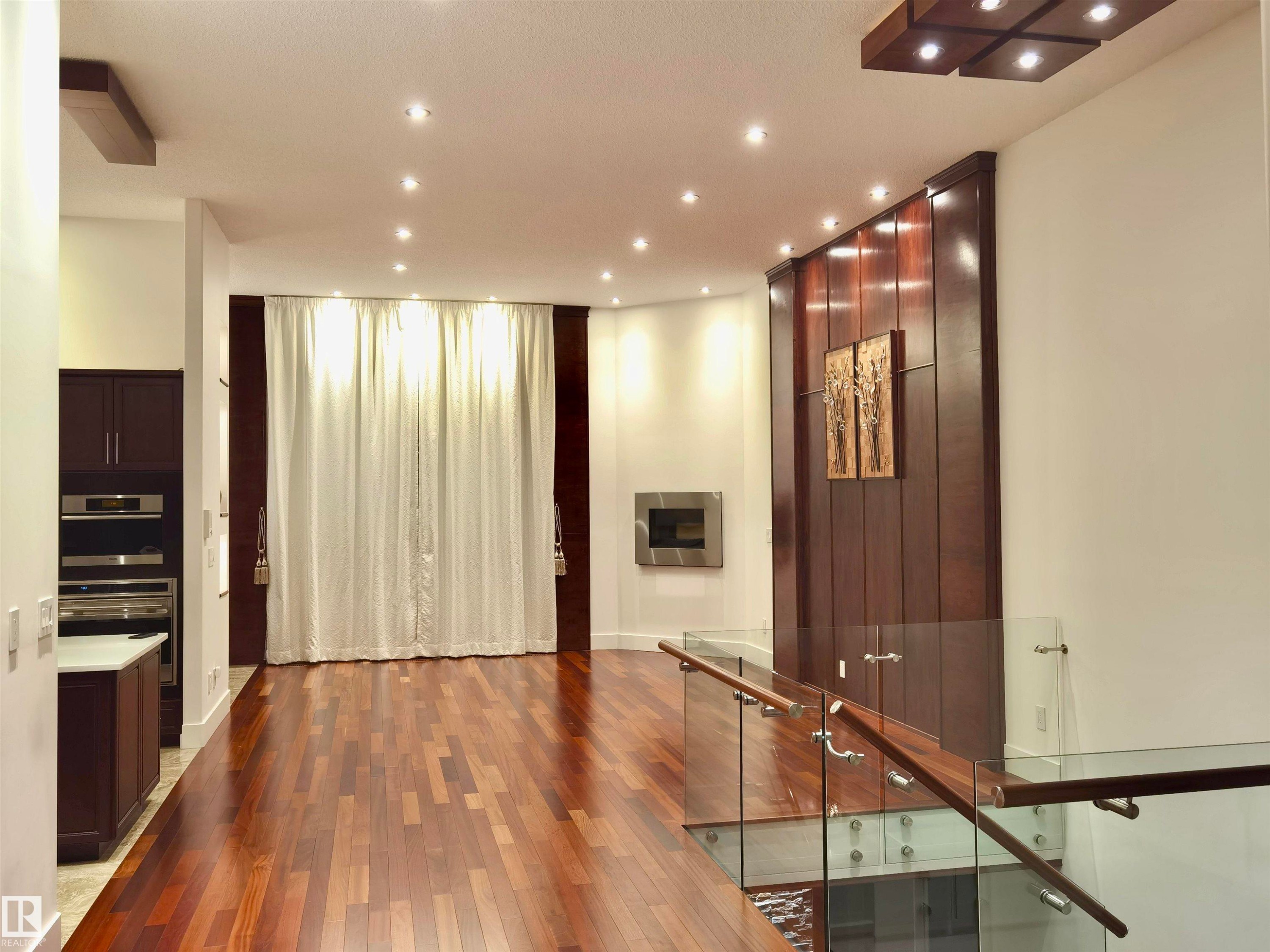 Unfurnished room with wood-type flooring, recessed lighting, and a glass covered fireplace - 169 Callaghan Drive, Edmonton, AB - Indoor Photo Showing Other Room
