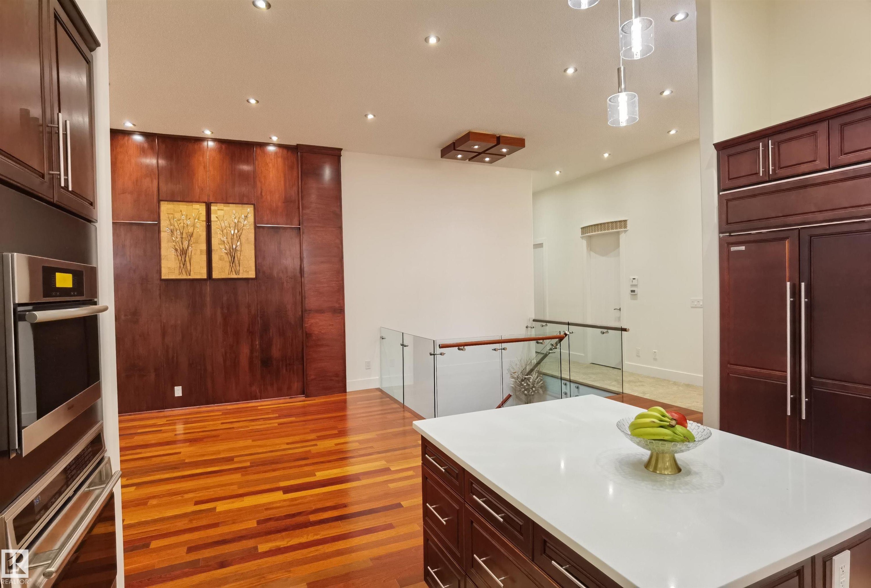 Kitchen with a kitchen island, stainless steel double oven, light wood-style floors, paneled refrigerator, and decorative light fixtures - 169 Callaghan Drive, Edmonton, AB - Indoor