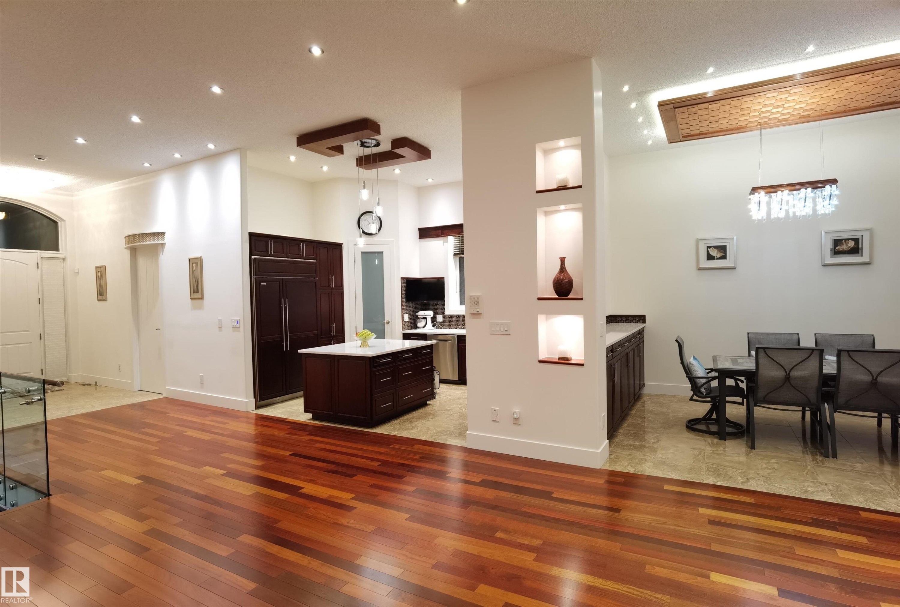 Kitchen featuring dark wood finish cabinetry, paneled fridge, a kitchen island, a high ceiling, and light wood-type flooring - 169 Callaghan Drive, Edmonton, AB - Indoor Photo Showing Other Room