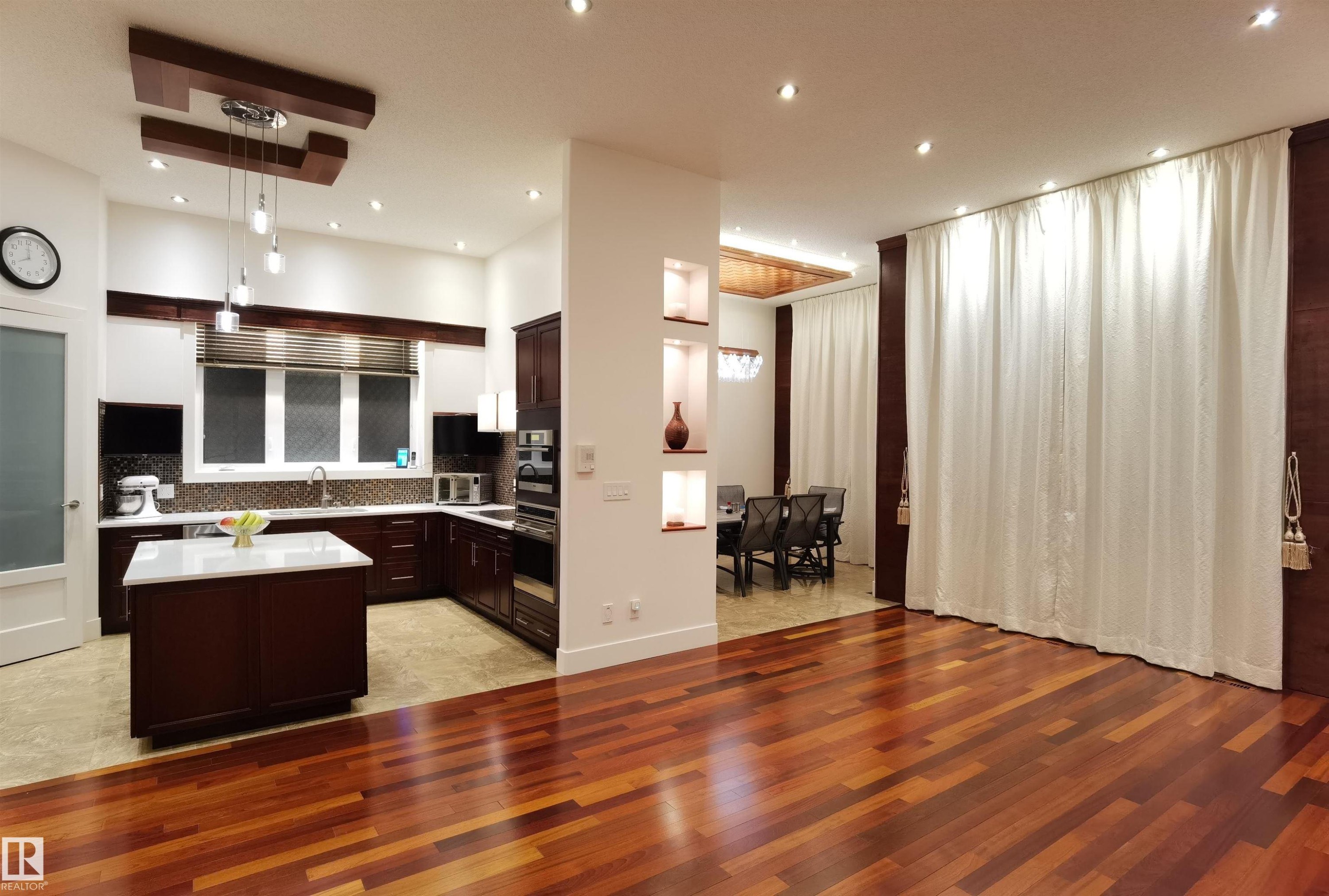 Kitchen with dark wood finish cabinets, light wood-type flooring, a center island, hanging light fixtures, and a high ceiling - 169 Callaghan Drive, Edmonton, AB - Indoor