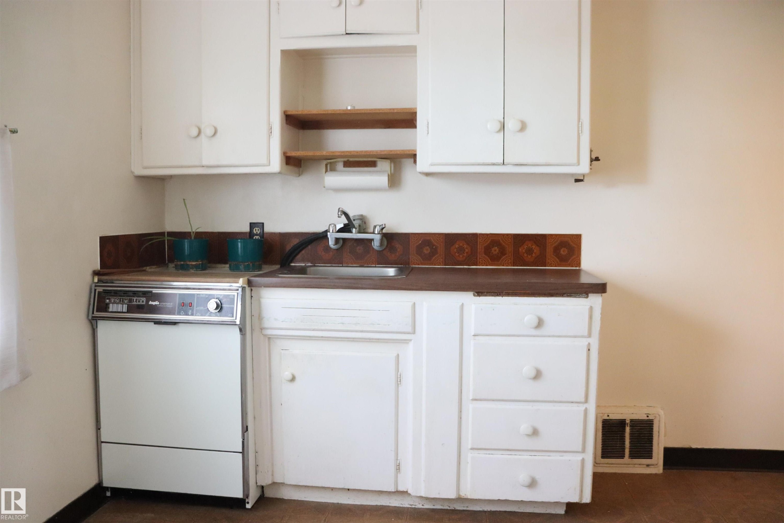 Kitchen with dark countertops, white cabinetry, open shelves, and dishwasher - 11250 72 Avenue, Edmonton, AB