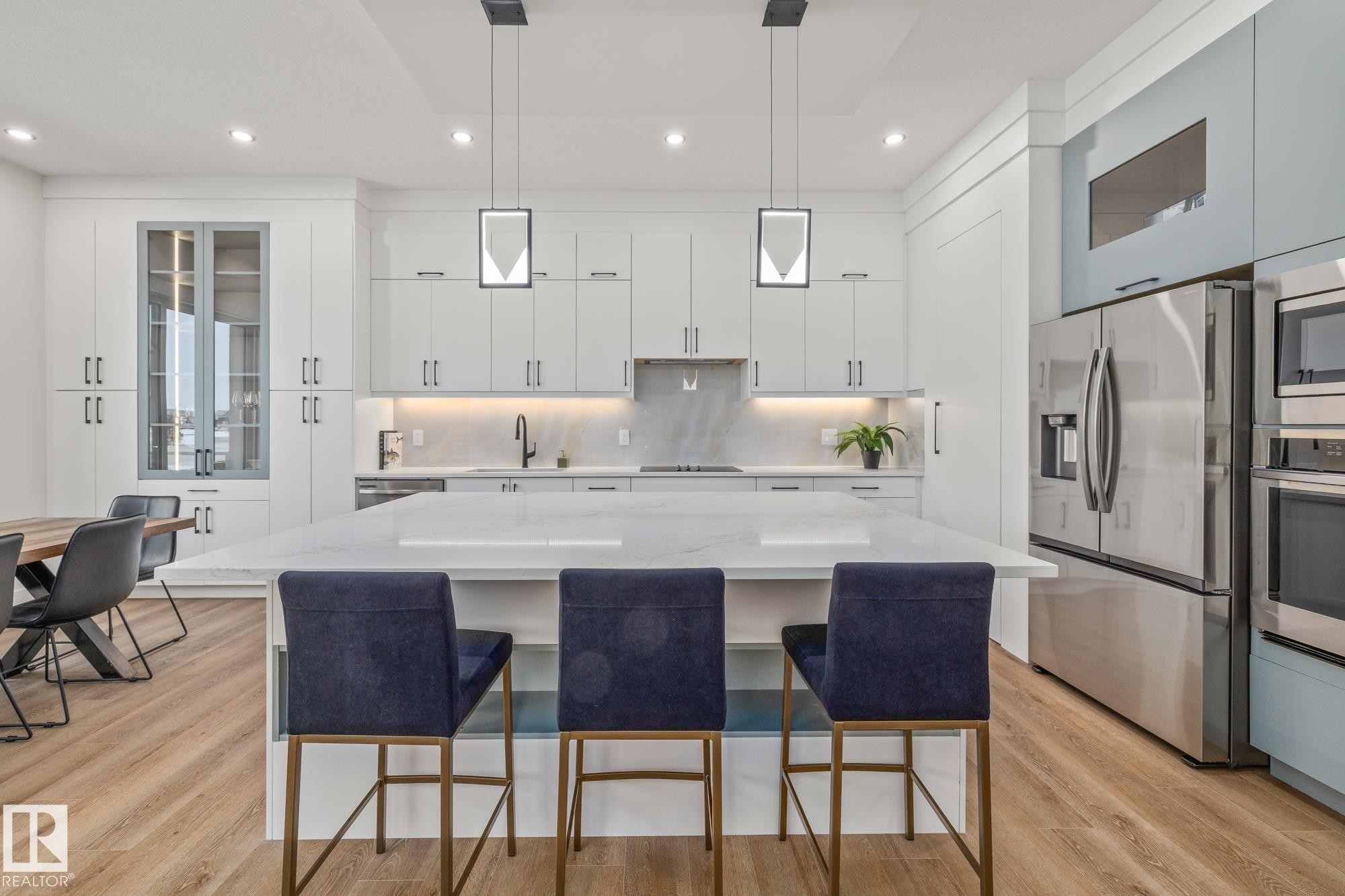 Kitchen with glass fronted cabinets, pendant lighting, a center island, stainless steel appliances, and a kitchen breakfast bar - 132 Edgewater Circle, Leduc, AB - Indoor Photo Showing Kitchen With Upgraded Kitchen