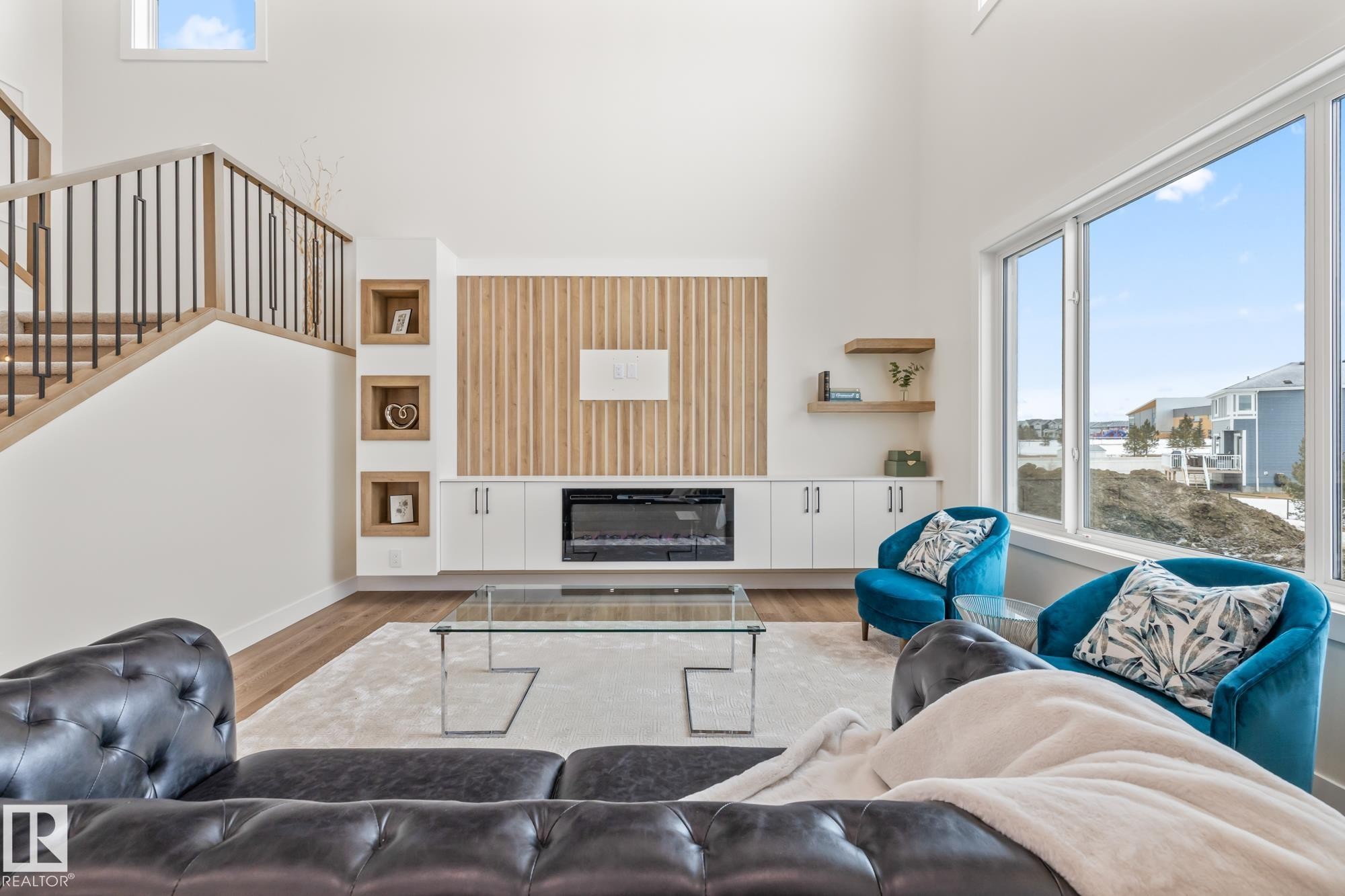 Living room featuring plenty of natural light, wood finished floors, a glass covered fireplace, and a high ceiling - 132 Edgewater Circle, Leduc, AB - Indoor Photo Showing Living Room