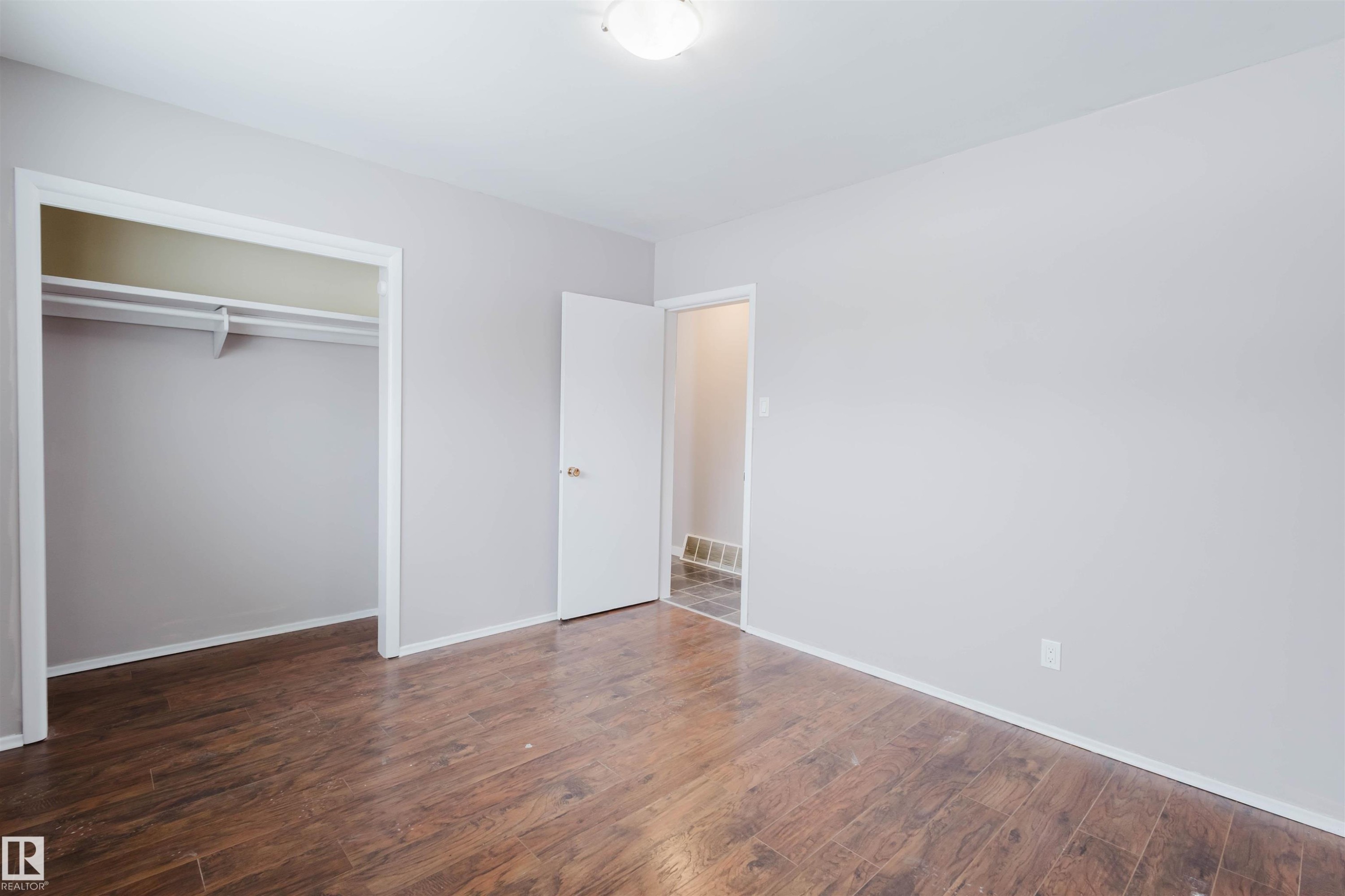 Unfurnished bedroom featuring dark wood-style floors and a closet - 6048 105B Street Nw, Edmonton, AB - Indoor Photo Showing Other Room