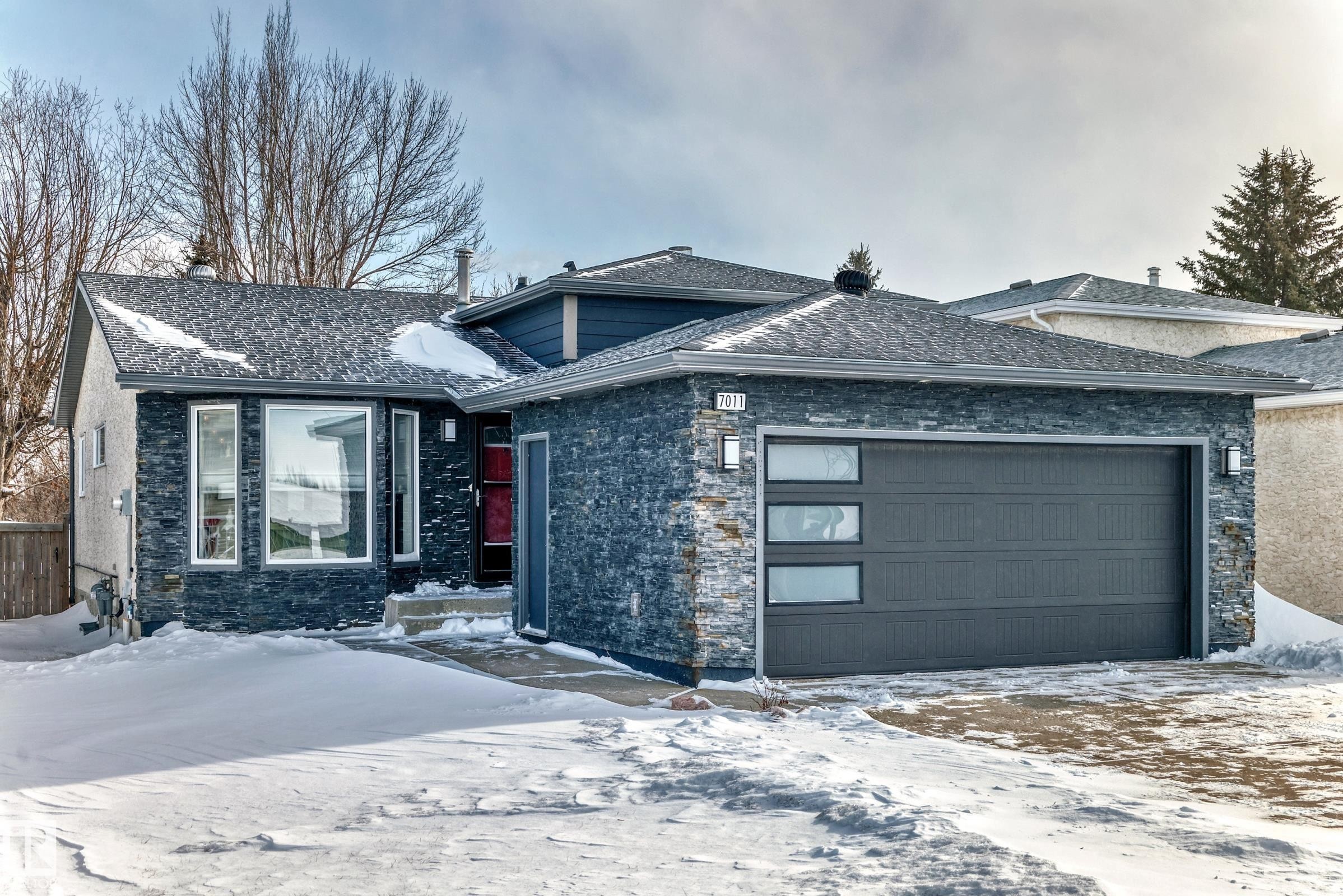 View of front of home with stone siding, a shingled roof, and a garage - 7011 190B Street, Edmonton, AB - Outdoor