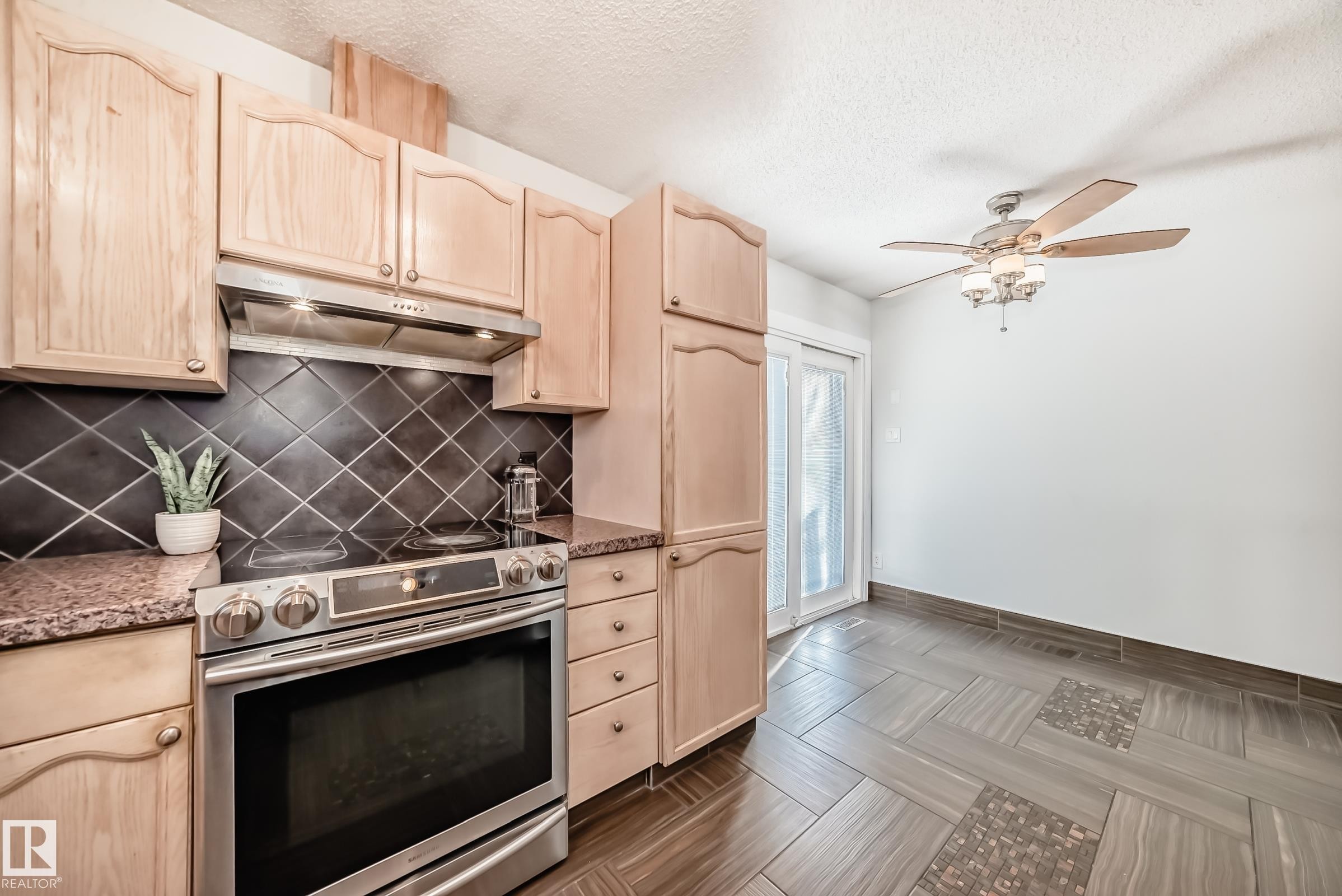 Kitchen with light wood finish cabinets, stainless steel range with electric stovetop, ceiling fan, and a textured ceiling - 7011 190B Street, Edmonton, AB - Indoor Photo Showing Kitchen
