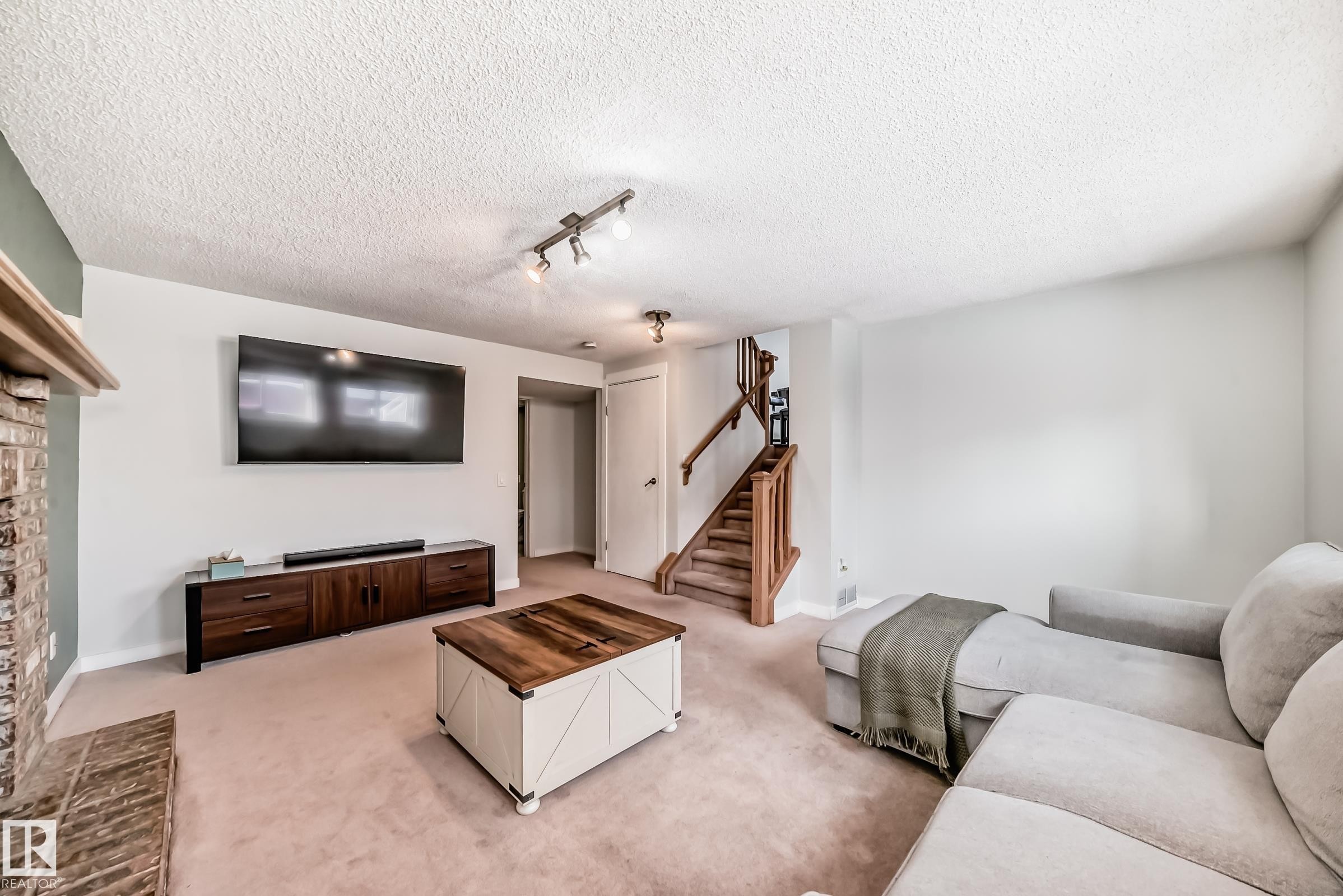 Living room with light colored carpet, track lighting, and a textured ceiling - 7011 190B Street, Edmonton, AB - Indoor Photo Showing Living Room