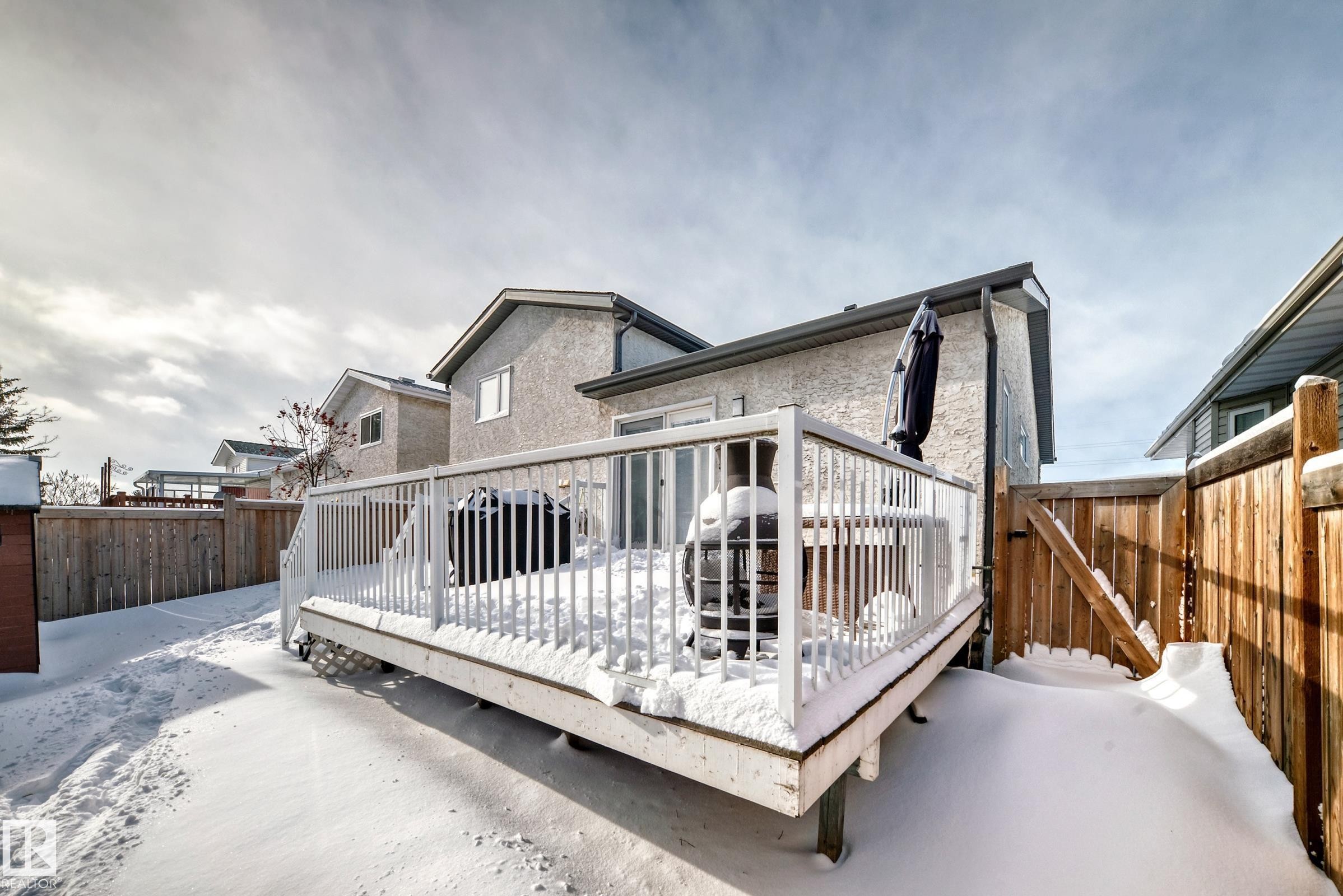 Back of house with a fenced backyard, a wooden deck, a gate, and stucco siding - 7011 190B Street, Edmonton, AB - Outdoor With Deck Patio Veranda With Exterior