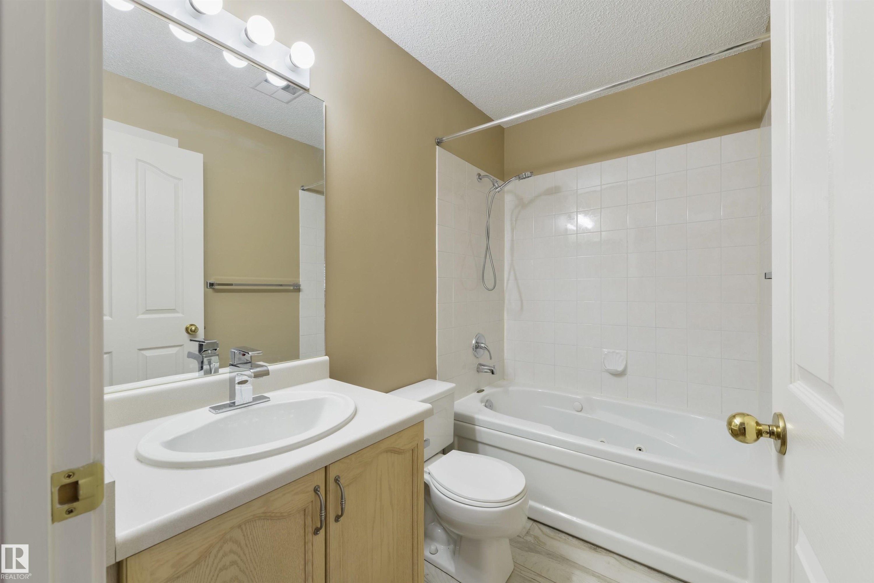 Full bathroom with vanity, a textured ceiling, and tub / shower combination - 232 15499 Castle Downs Road, Edmonton, AB - Indoor Photo Showing Bathroom