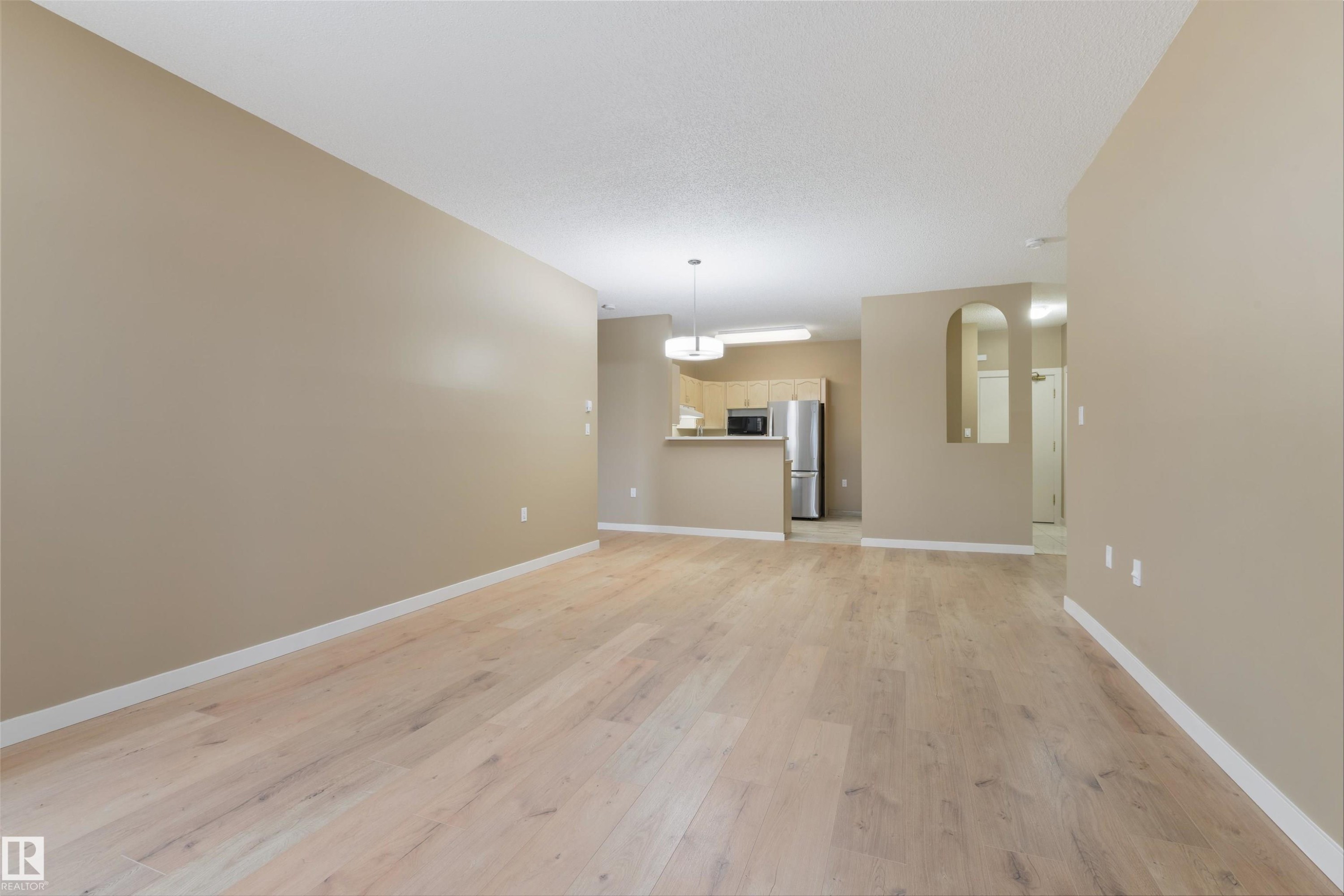 Unfurnished living room with light wood finished floors and arched walkways - 232 15499 Castle Downs Road, Edmonton, AB - Indoor Photo Showing Other Room