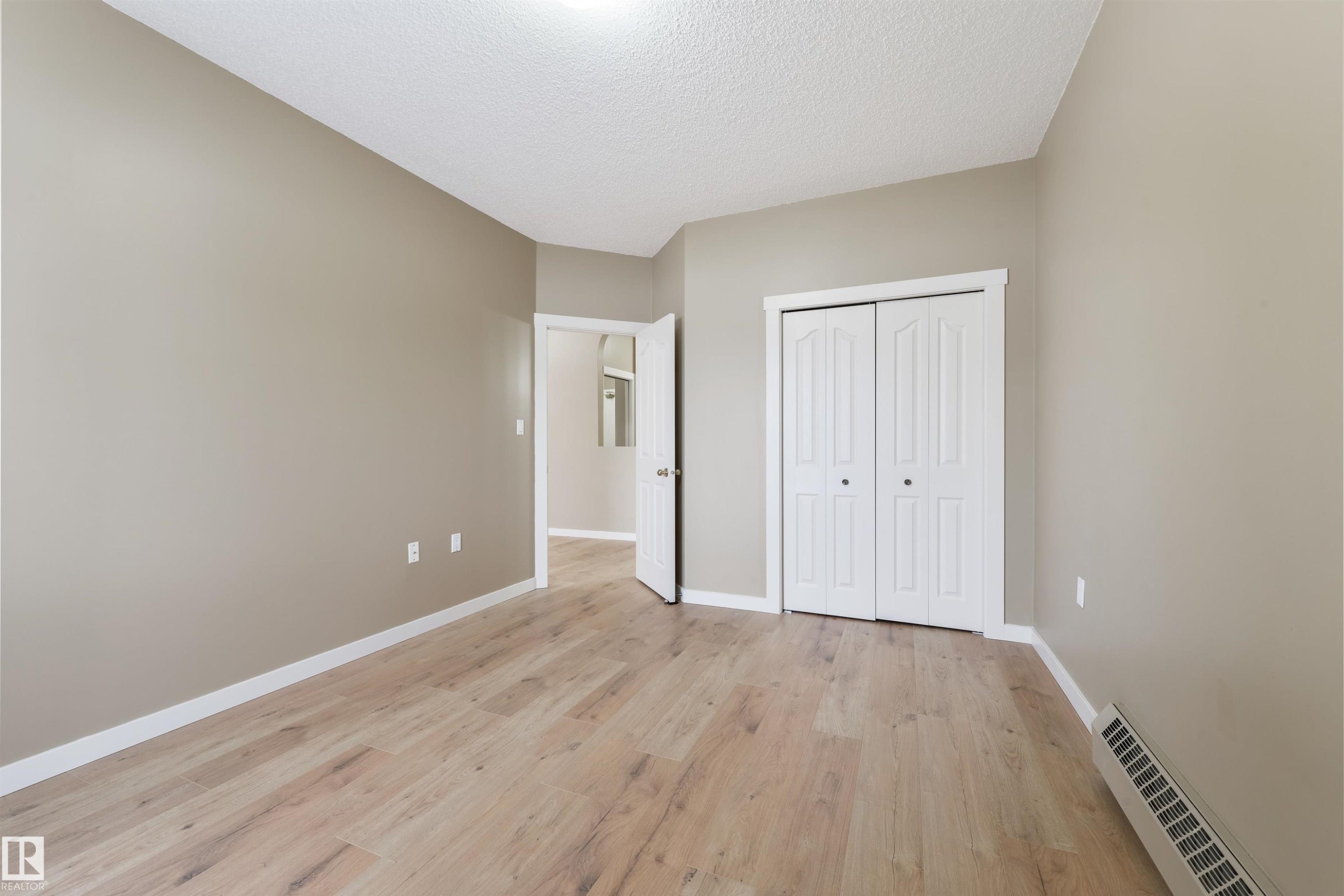 Unfurnished bedroom with light wood finished floors, a closet, and a textured ceiling - 232 15499 Castle Downs Road, Edmonton, AB - Indoor Photo Showing Other Room