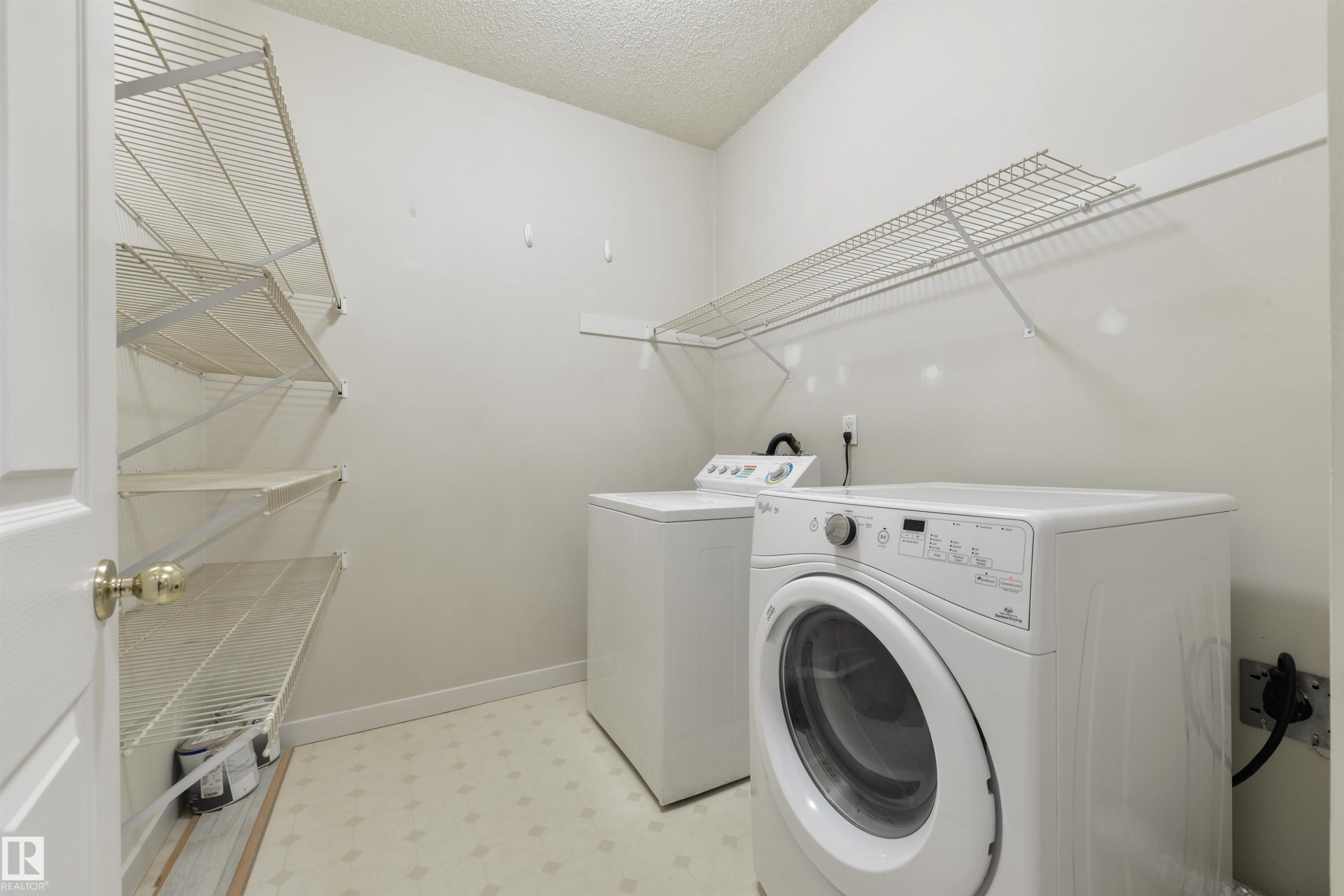 Laundry room featuring light flooring, a textured ceiling, and washing machine and clothes dryer - 232 15499 Castle Downs Road, Edmonton, AB - Indoor Photo Showing Laundry Room