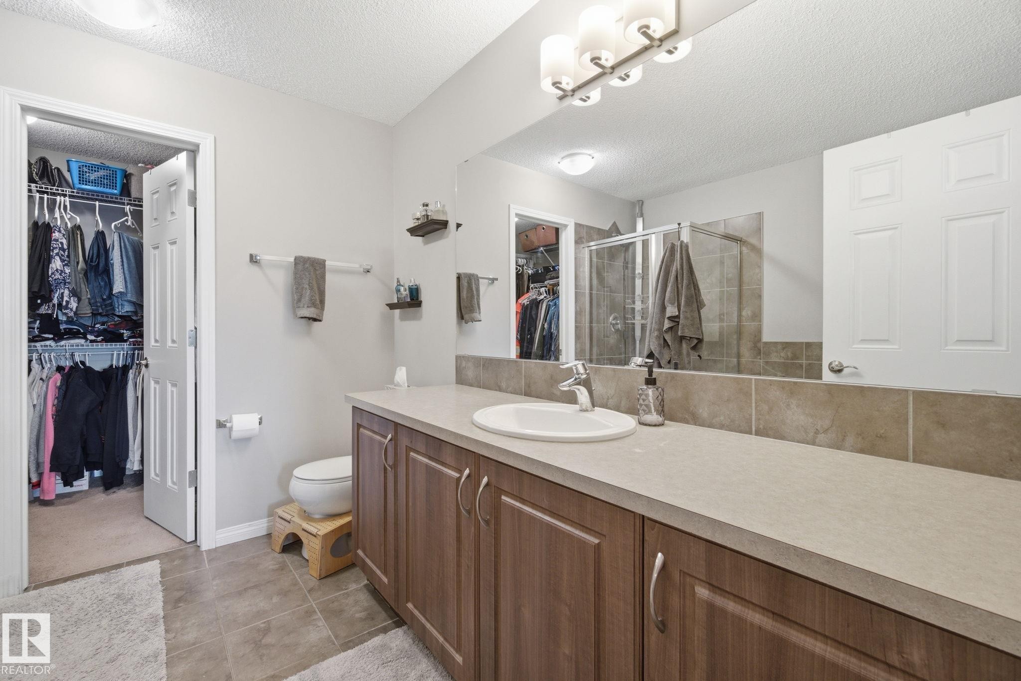Bathroom featuring a walk in closet, a shower stall, vanity, a textured ceiling, and light tile patterned flooring - 3087 Arthurs Crescent, Edmonton, AB - Indoor Photo Showing Bathroom