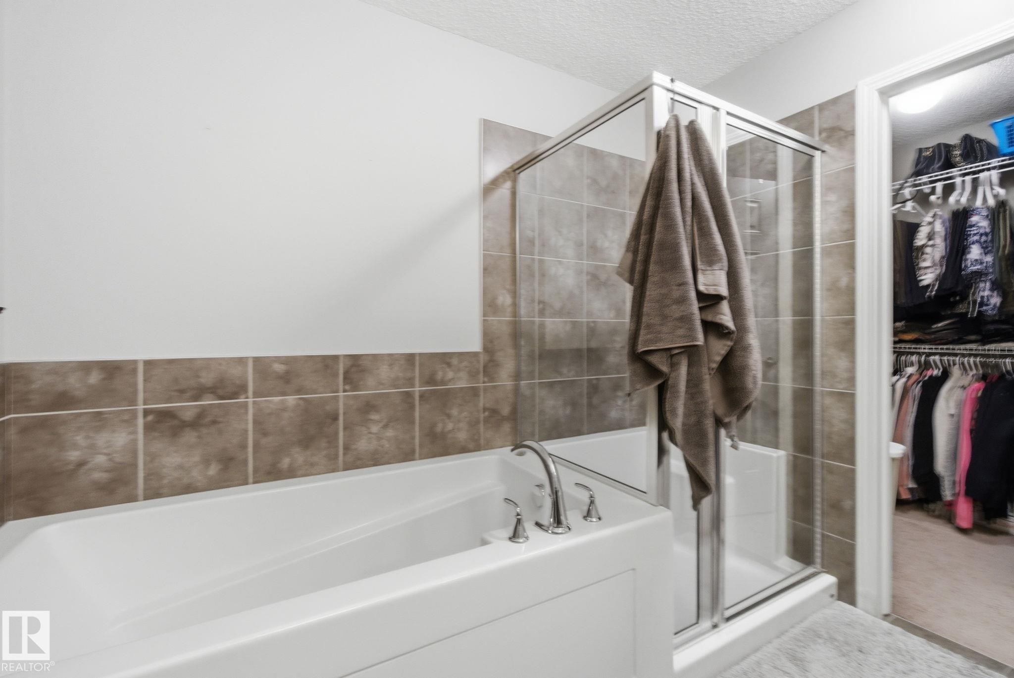 Full bathroom featuring a textured ceiling, a shower stall, a bath, and a walk in closet - 3087 Arthurs Crescent, Edmonton, AB - Indoor Photo Showing Bathroom