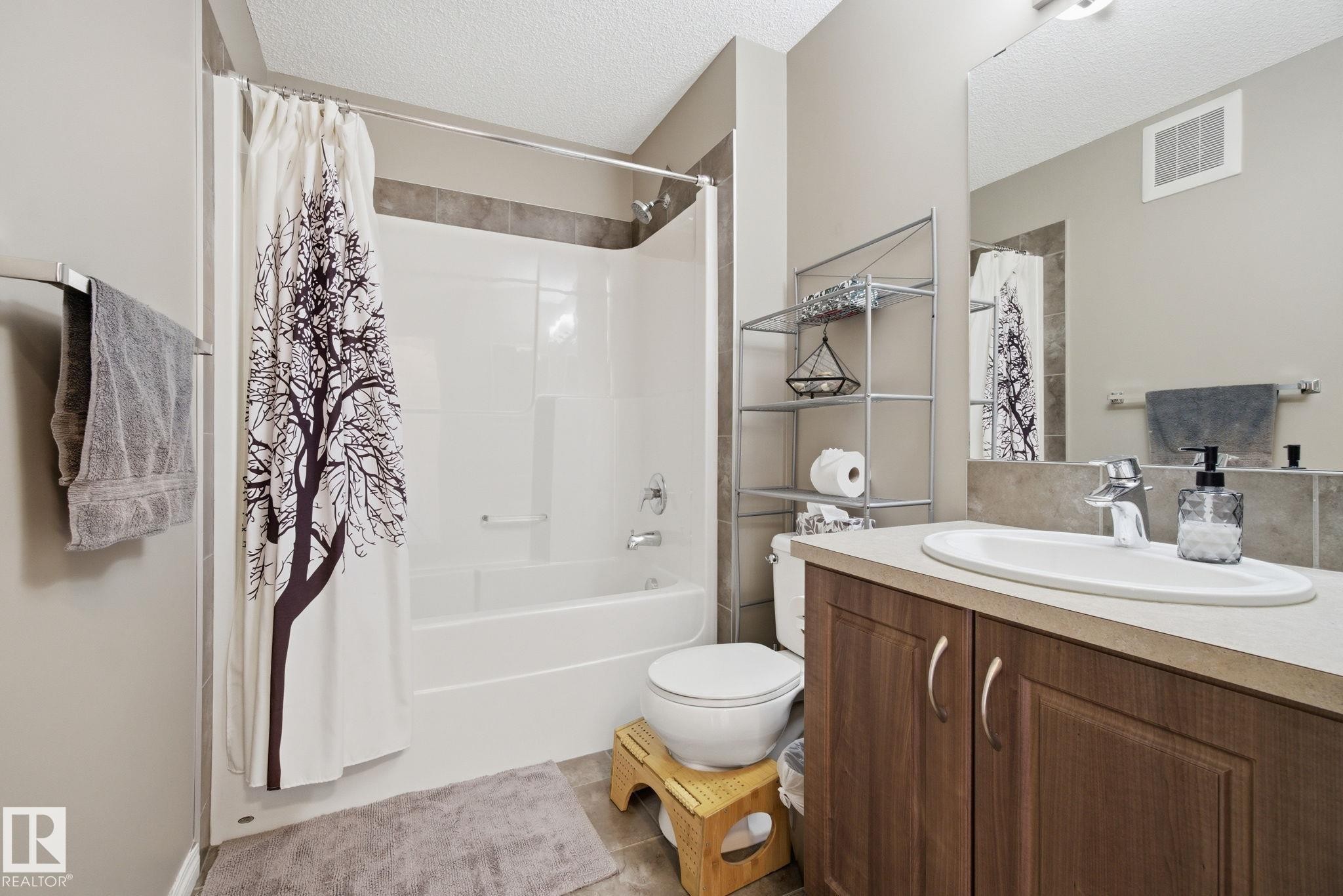Full bathroom with vanity, a textured ceiling, shower / bathtub combination with curtain, and light tile patterned flooring - 3087 Arthurs Crescent, Edmonton, AB - Indoor Photo Showing Bathroom