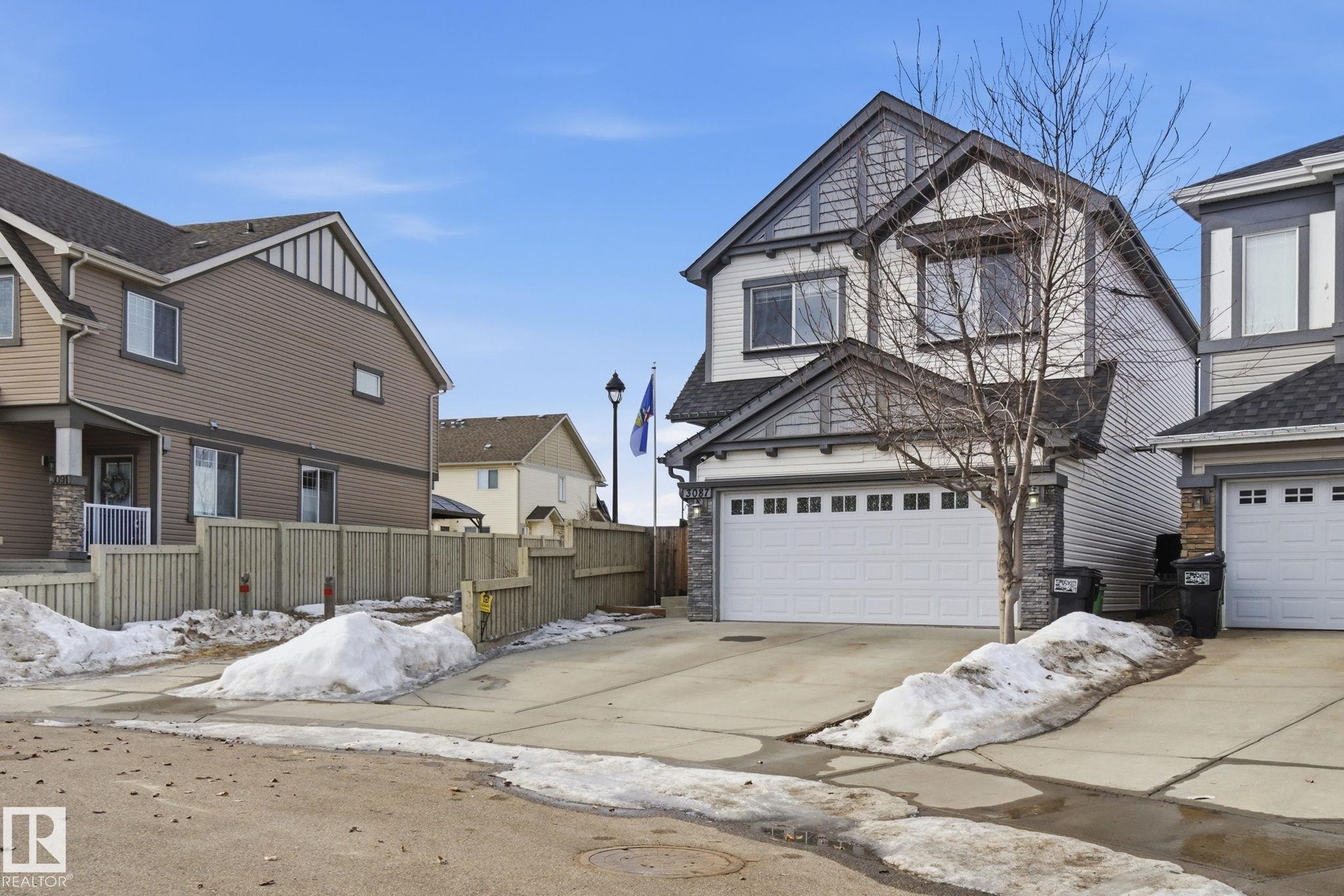 View of front of home with stone siding, driveway, board and batten siding, and a garage - 3087 Arthurs Crescent, Edmonton, AB - Outdoor