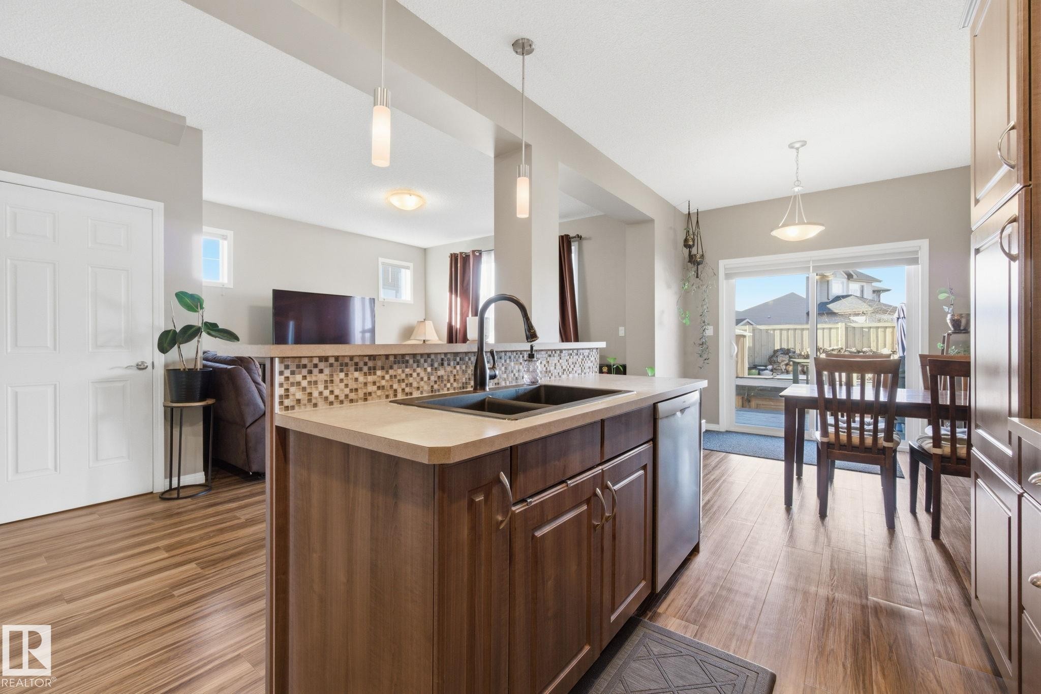 Kitchen featuring decorative light fixtures, an island with sink, open floor plan, and dark wood-type flooring - 3087 Arthurs Crescent, Edmonton, AB - Indoor Photo Showing Kitchen With Double Sink