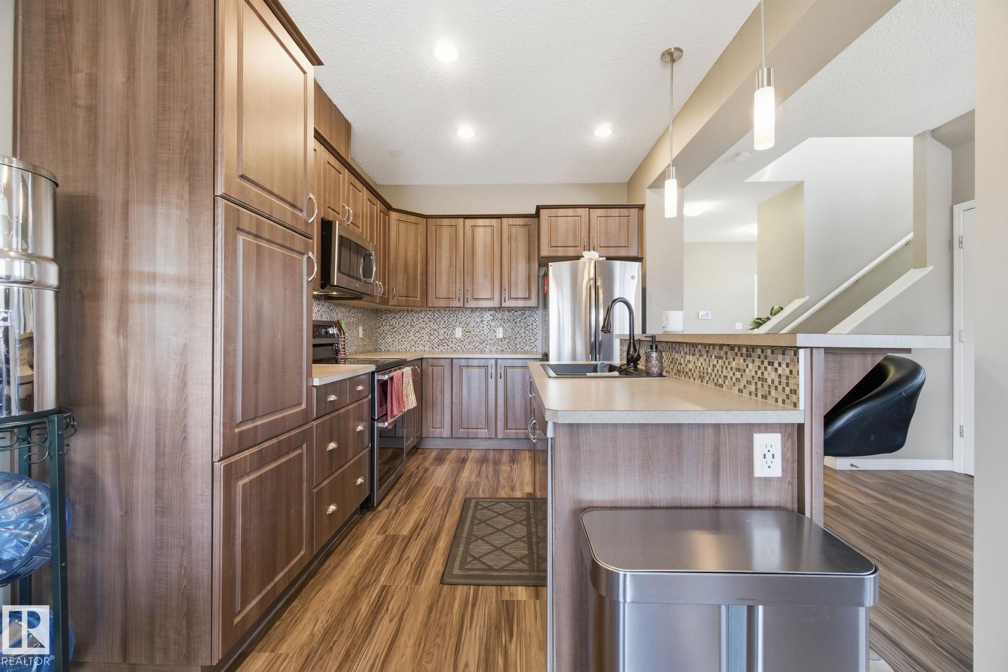 Kitchen featuring stainless steel appliances, light countertops, hanging light fixtures, and tasteful backsplash - 3087 Arthurs Crescent, Edmonton, AB - Indoor Photo Showing Kitchen With Stainless Steel Kitchen With Upgraded Kitchen