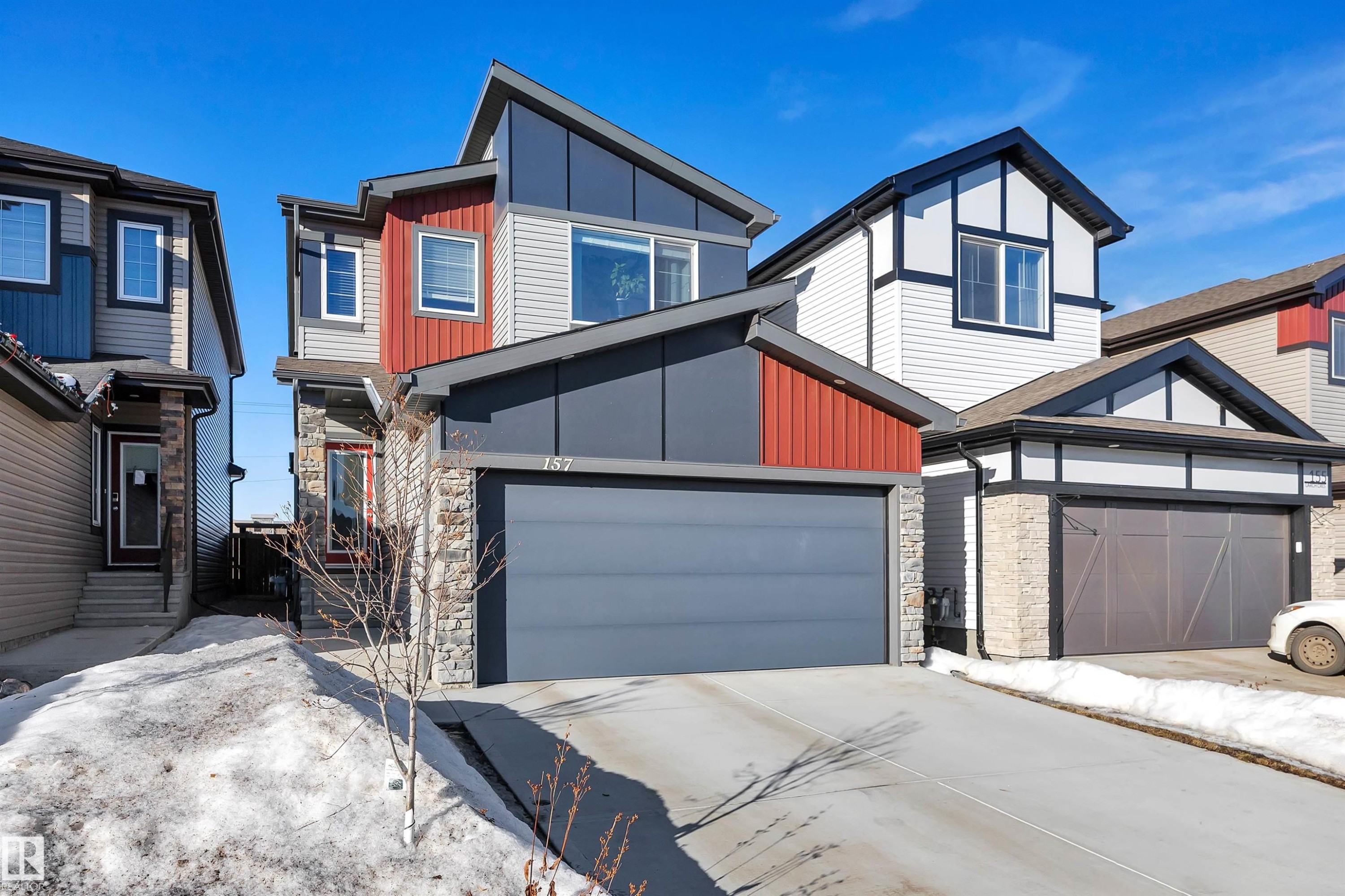 Contemporary home featuring stone siding, board and batten siding, concrete driveway, and a garage - 157 Larch Crescent, Leduc, AB - Outdoor