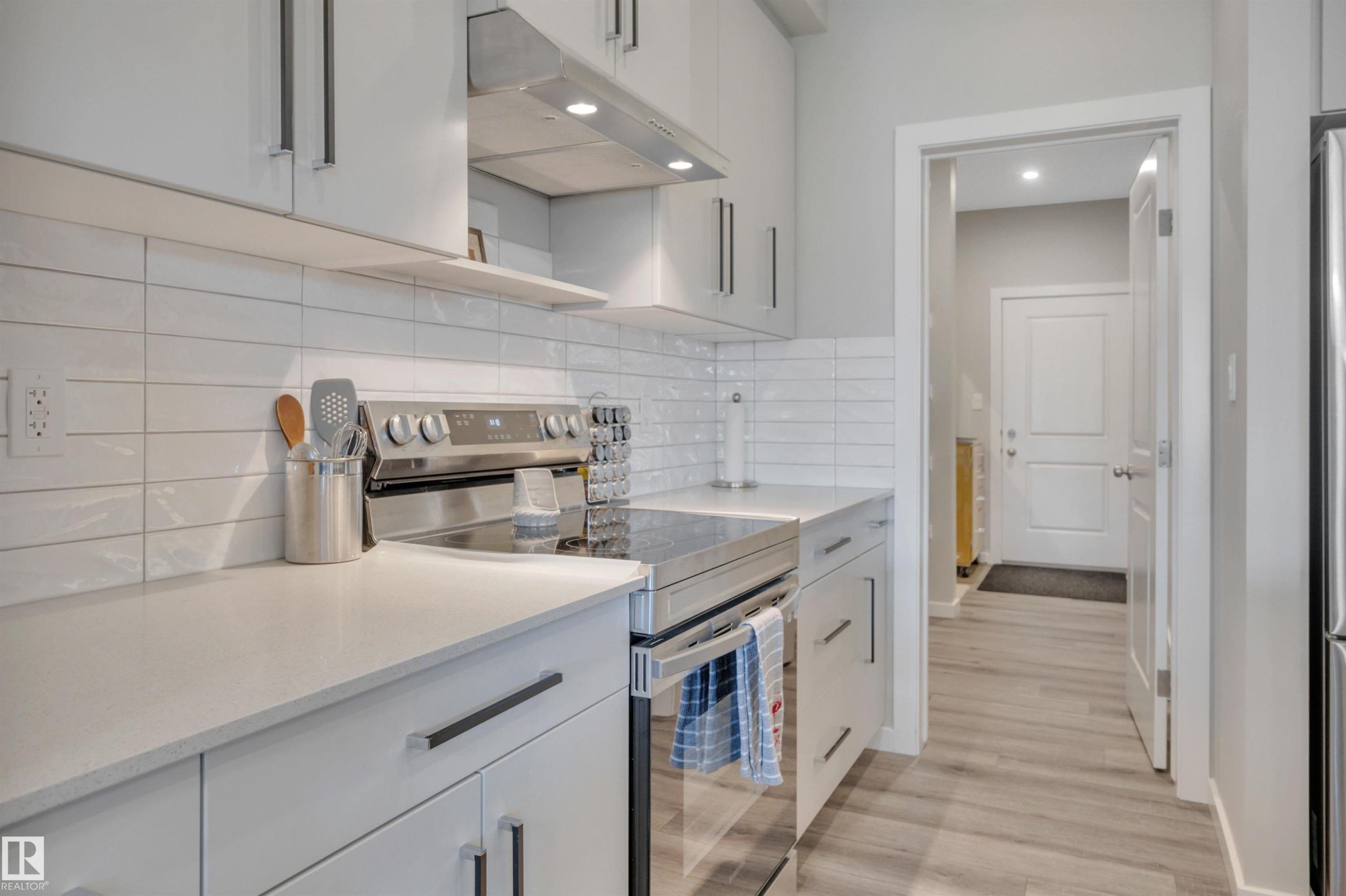 Kitchen featuring stainless steel electric stove, light stone countertops, decorative backsplash, recessed lighting, and light wood-style flooring - 157 Larch Crescent, Leduc, AB - Indoor Photo Showing Kitchen