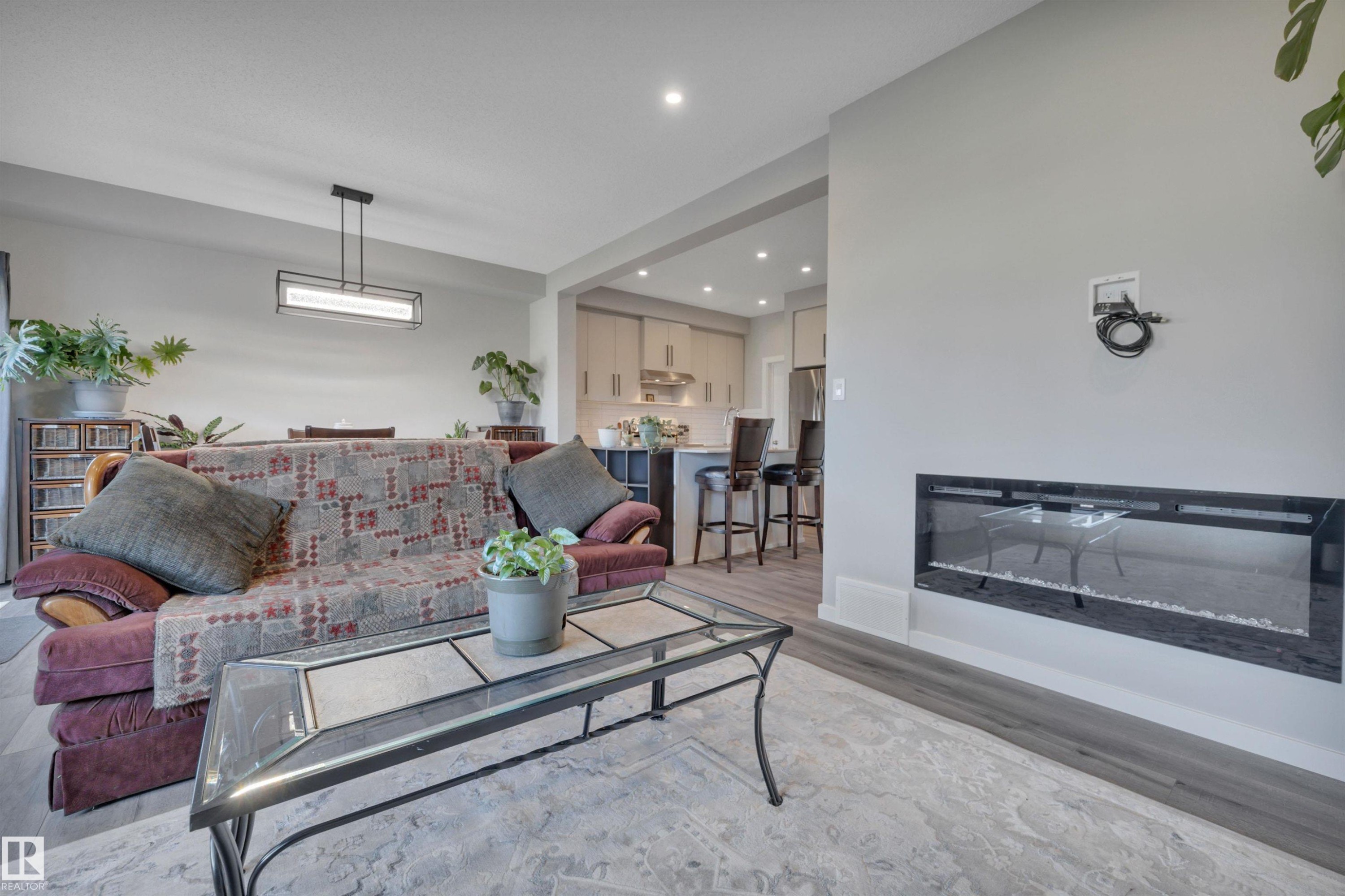 Living area with a glass covered fireplace, recessed lighting, and light wood-type flooring - 157 Larch Crescent, Leduc, AB - Indoor Photo Showing Living Room With Fireplace
