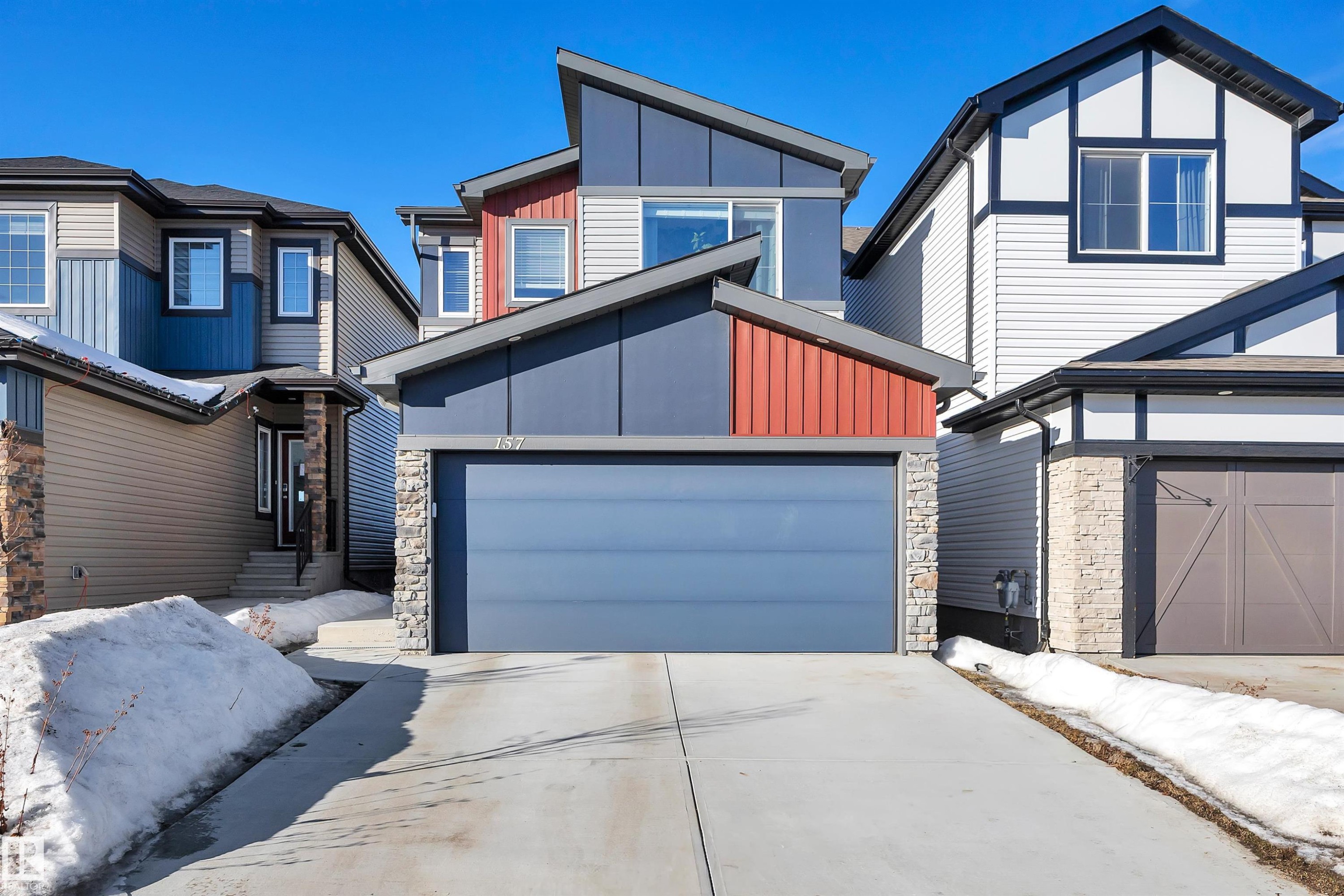 Contemporary home with stone siding, board and batten siding, and driveway - 157 Larch Crescent, Leduc, AB - Outdoor
