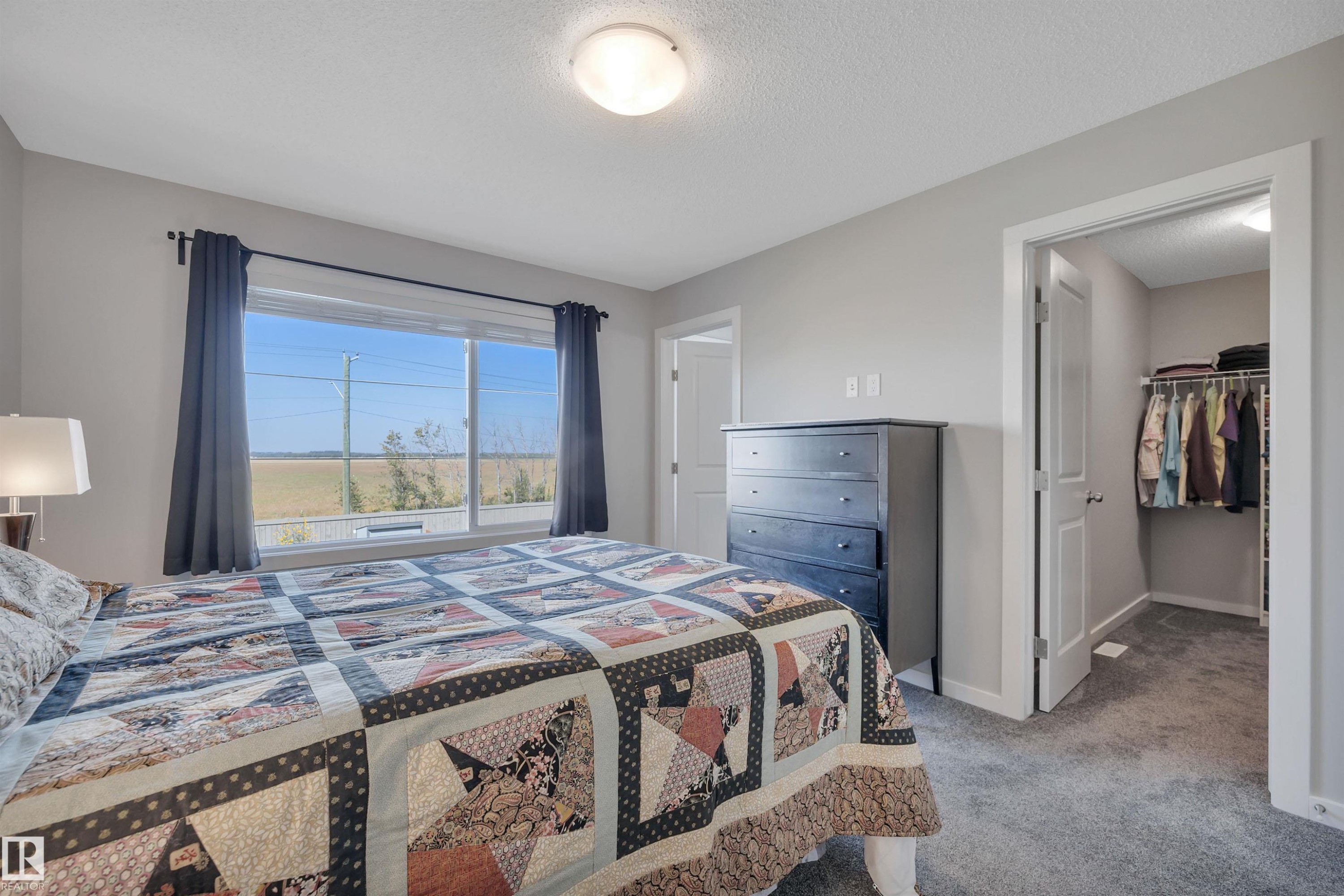 Bedroom with a spacious closet, light carpet, and a textured ceiling - 157 Larch Crescent, Leduc, AB - Indoor Photo Showing Bedroom