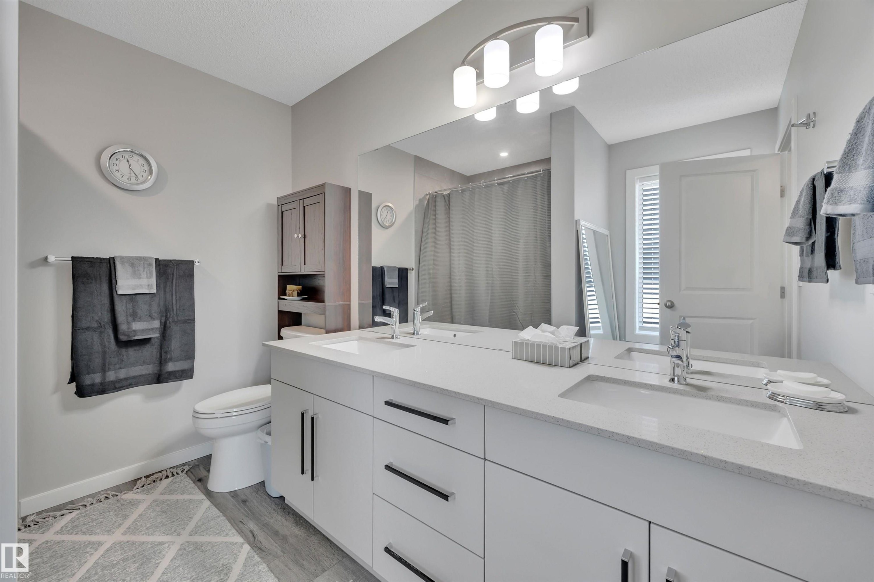Bathroom with curtained shower, double vanity, and light wood-style flooring - 157 Larch Crescent, Leduc, AB - Indoor Photo Showing Bathroom