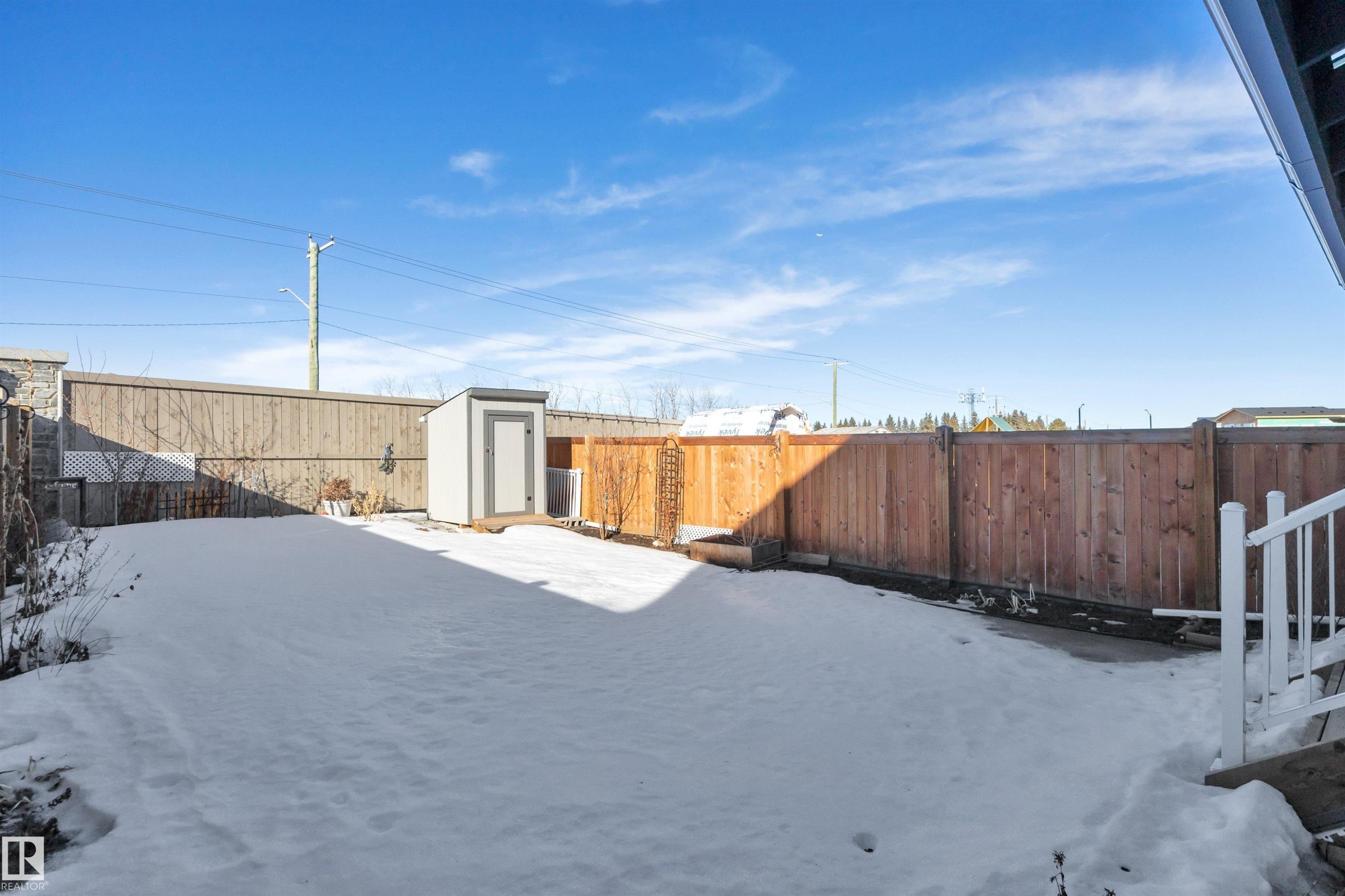 Yard layered in snow featuring a fenced backyard and a shed - 157 Larch Crescent, Leduc, AB - Outdoor
