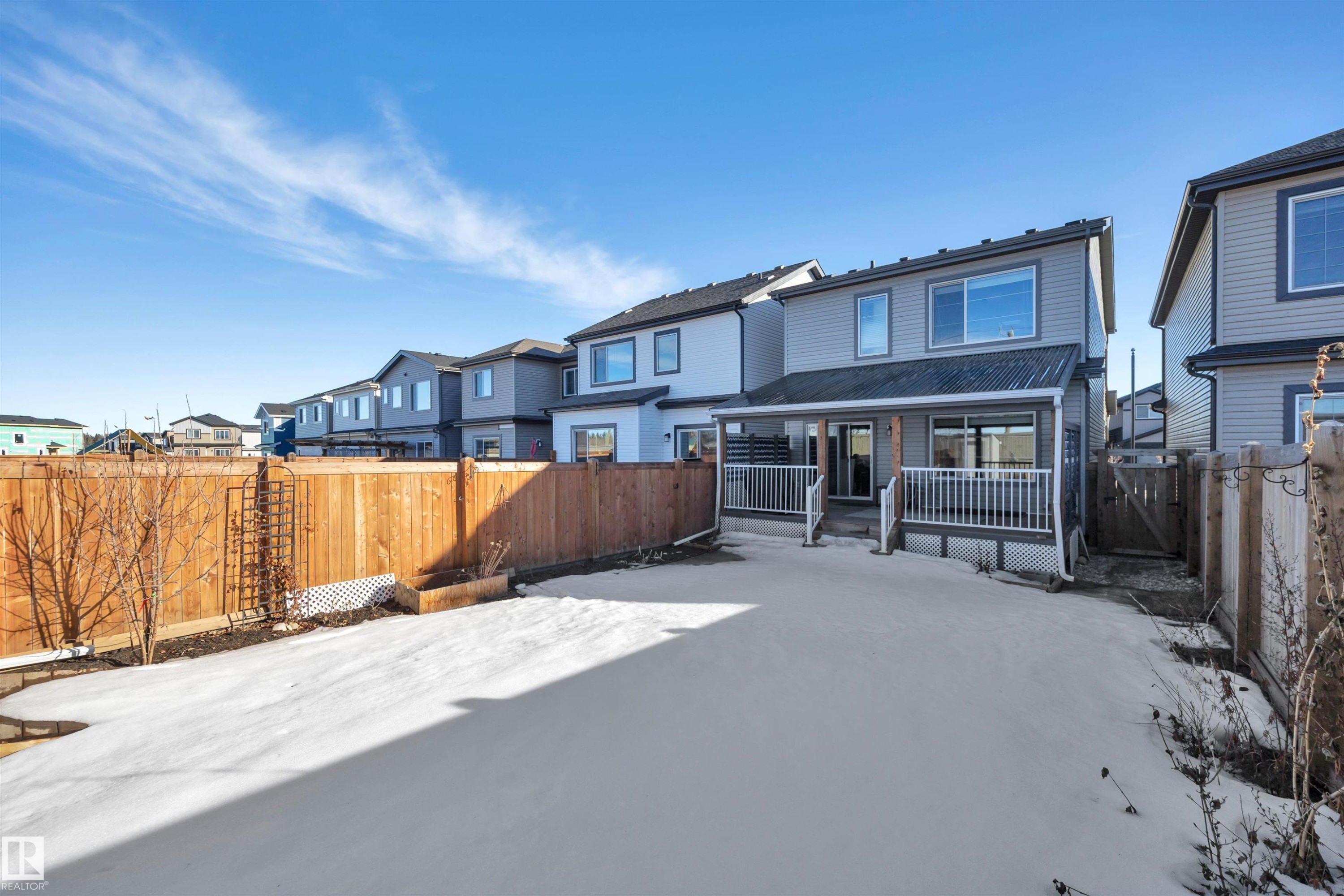 Snow covered house with a fenced backyard, a deck, and a residential view - 157 Larch Crescent, Leduc, AB - Outdoor With Deck Patio Veranda