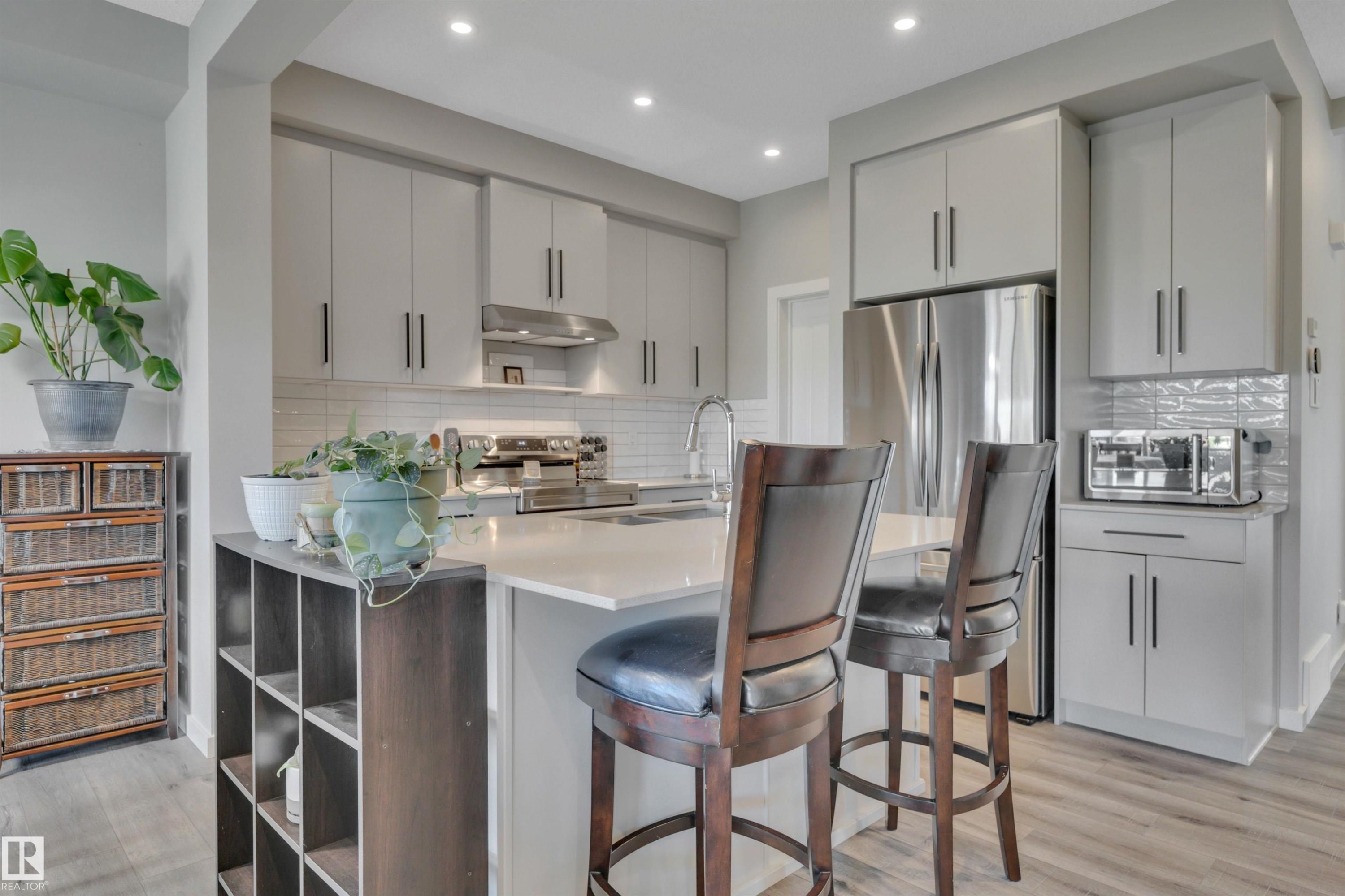 Kitchen featuring light wood-style flooring, stainless steel appliances, tasteful backsplash, a kitchen bar, and modern cabinets - 157 Larch Crescent, Leduc, AB - Indoor Photo Showing Kitchen With Upgraded Kitchen