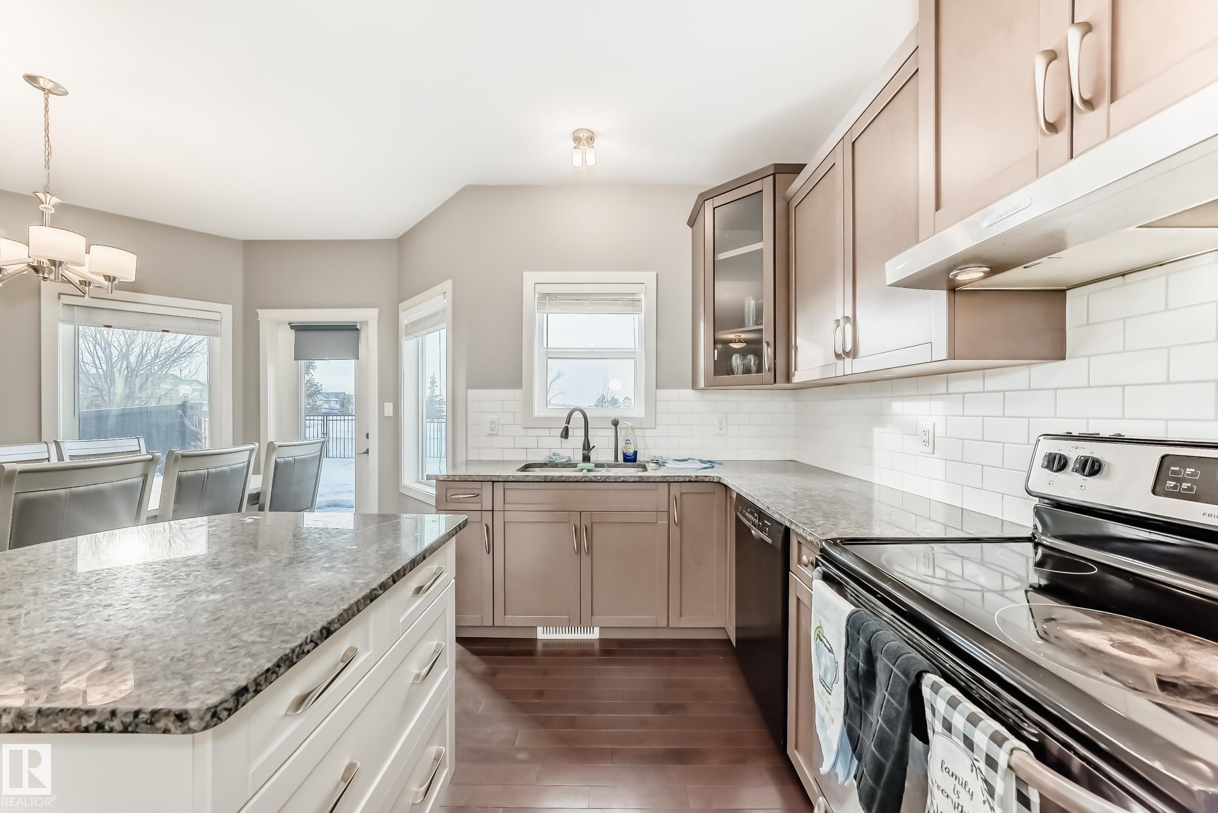 Kitchen with stainless steel electric stove, dark stone counters, glass fronted cabinets, backsplash, and dark wood-style floors - 1908 69 Street, Edmonton, AB - Indoor Photo Showing Kitchen With Upgraded Kitchen