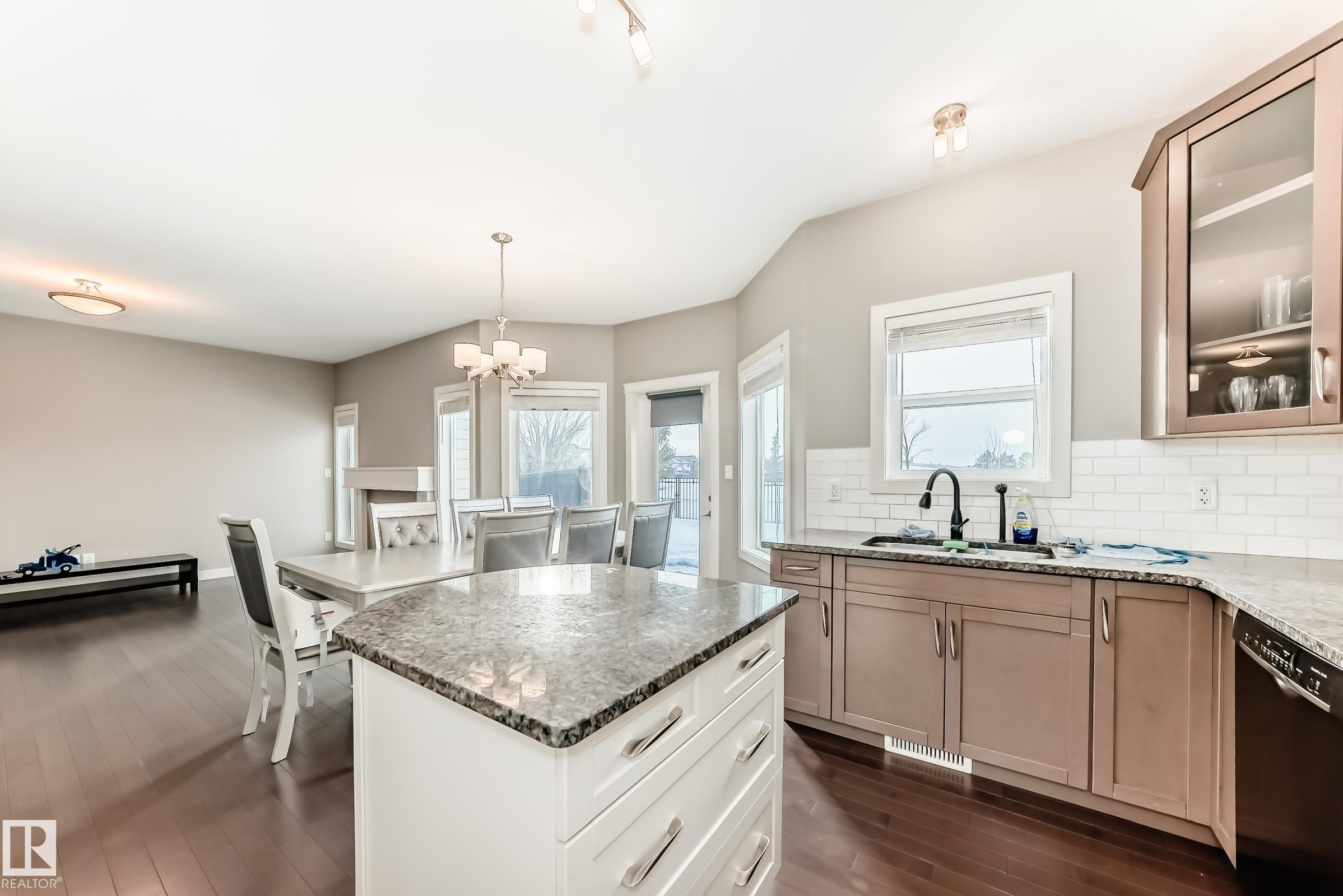 Two tone kitchen featuring backsplash, dark stone counters, a kitchen island, black dishwasher, and glass insert cabinets - 1908 69 Street, Edmonton, AB - Indoor Photo Showing Kitchen With Upgraded Kitchen