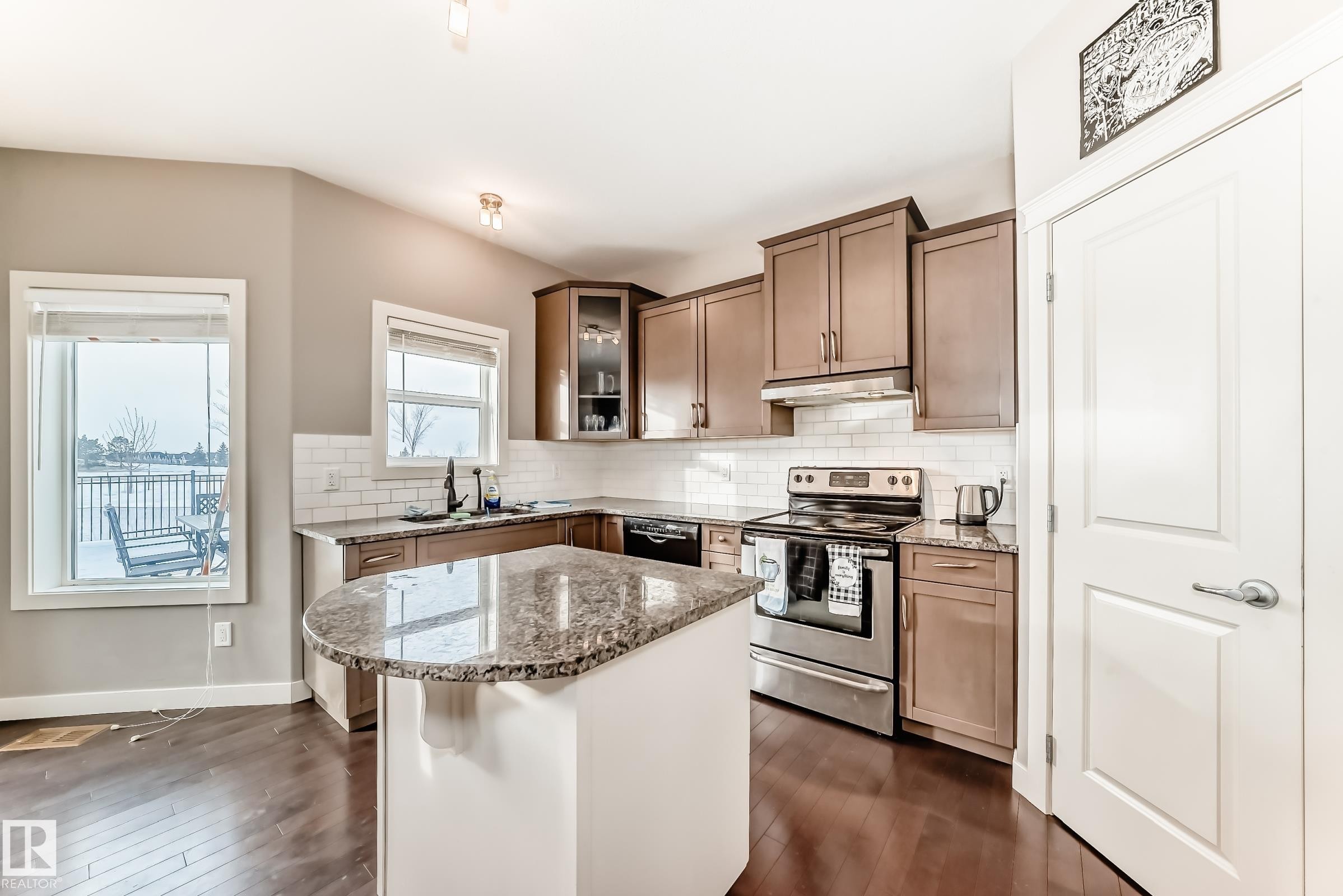 Kitchen with electric range, light stone counters, dark wood-style flooring, and glass fronted cabinets - 1908 69 Street, Edmonton, AB - Indoor Photo Showing Kitchen With Upgraded Kitchen