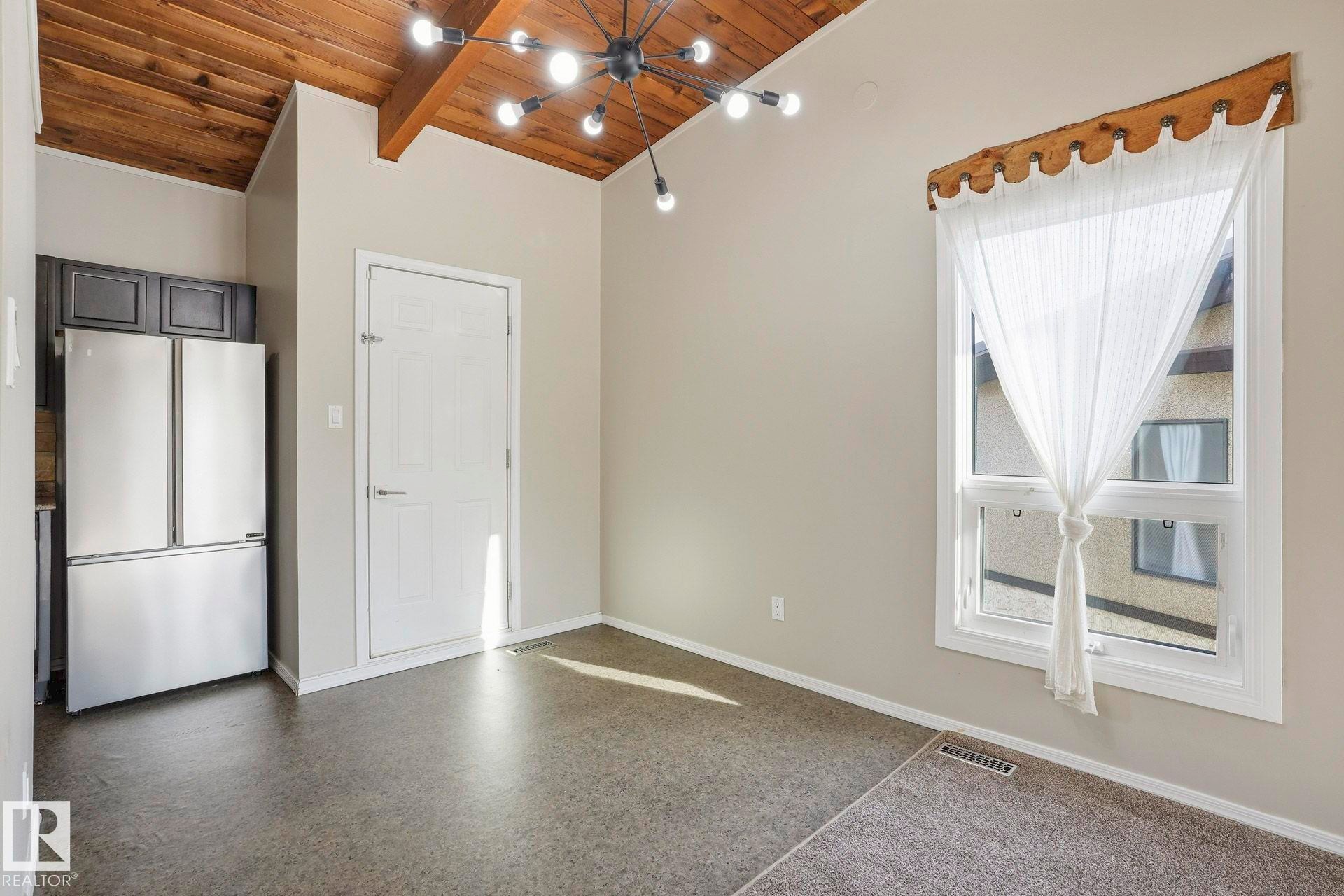 Empty room featuring a wood ceiling with exposed beams and light speckled floor - Edmonton, AB - Indoor Photo Showing Other Room